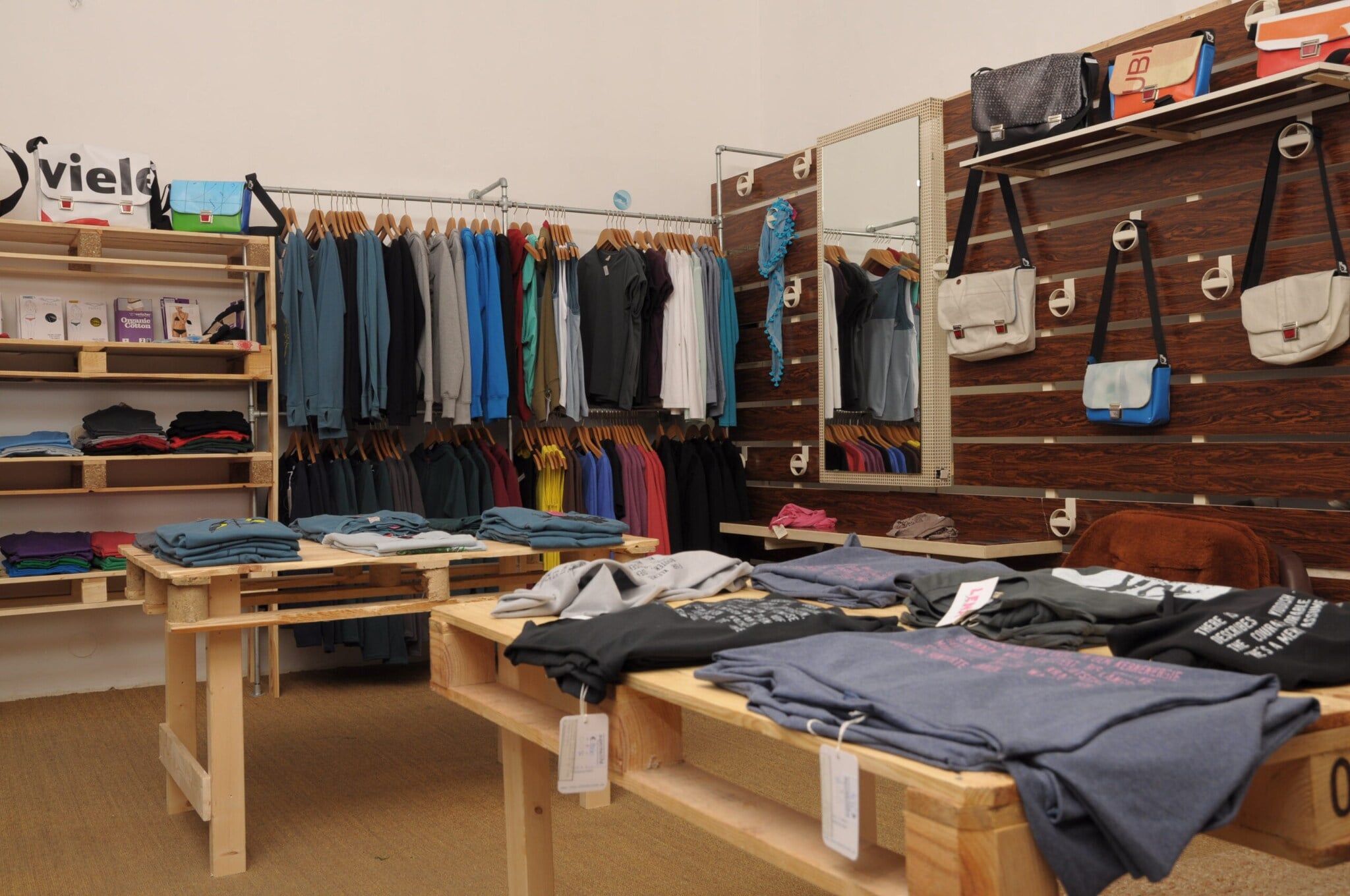 Kleidungsstücke und Taschen hängen an Kleiderständern und liegen auf Tischen. Kleidungsstücke und Taschen hängen an Kleiderständern und liegen auf Tischen.