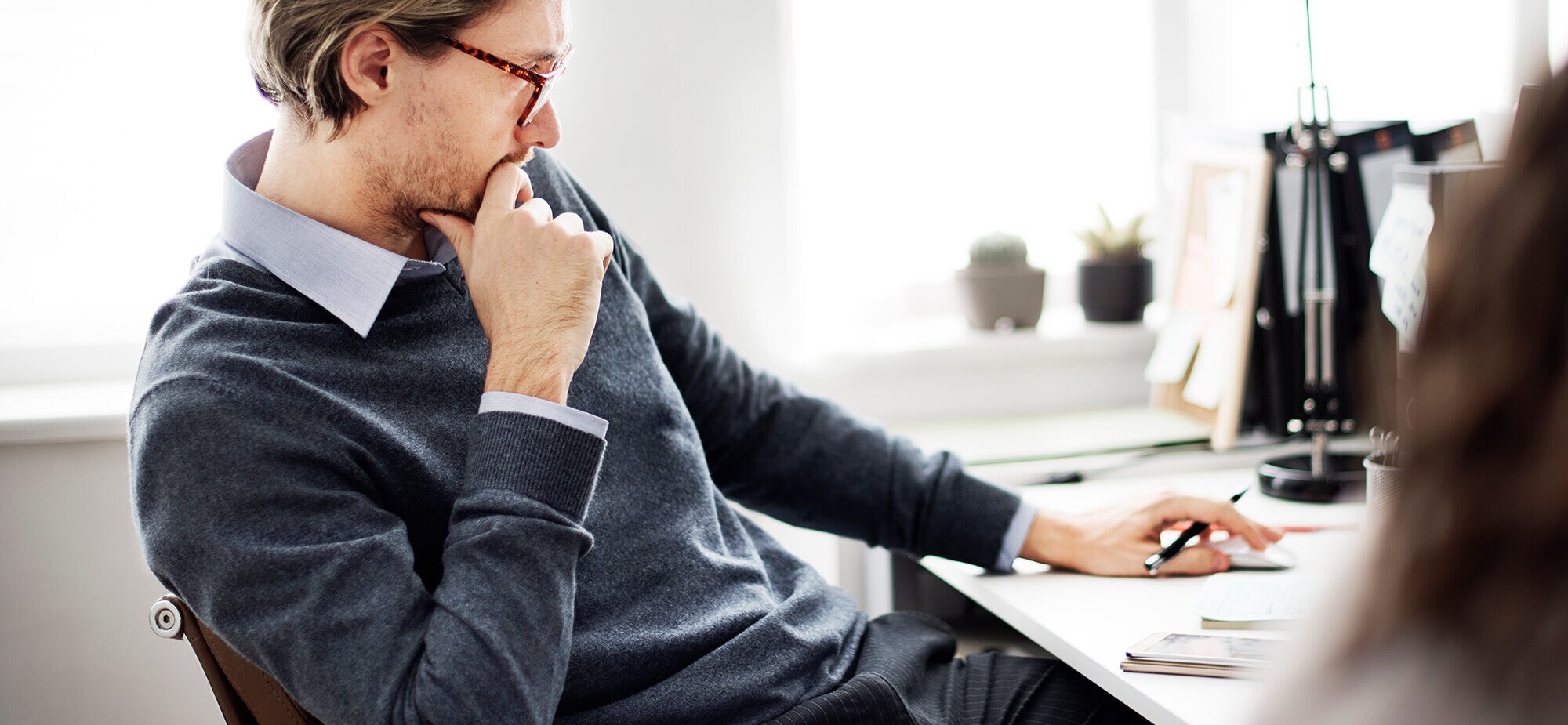 Büromitarbeiter sitzt nachdenklich an seinem Schreibtisch