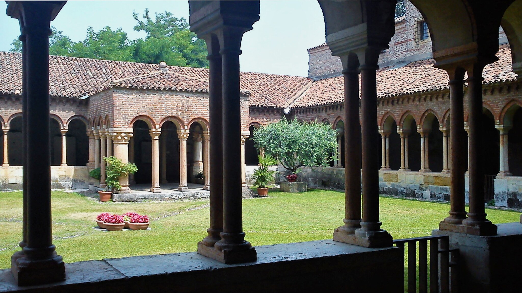 Kreuzgang in einem Kloster mit Innenhof mit Rasenfläche.