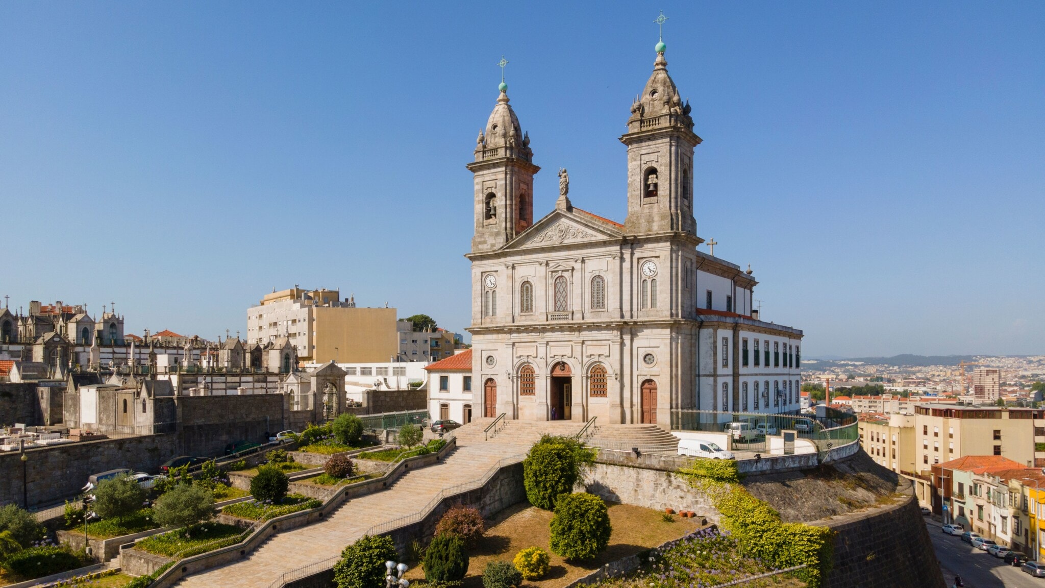 Kirche mit Zwillingstürmen auf einem Hügel über den Dächern einer südländischen Großstadt unter blauem Himmel. Kirche mit Zwillingstürmen auf einem Hügel über den Dächern einer südländischen Großstadt unter blauem Himmel.