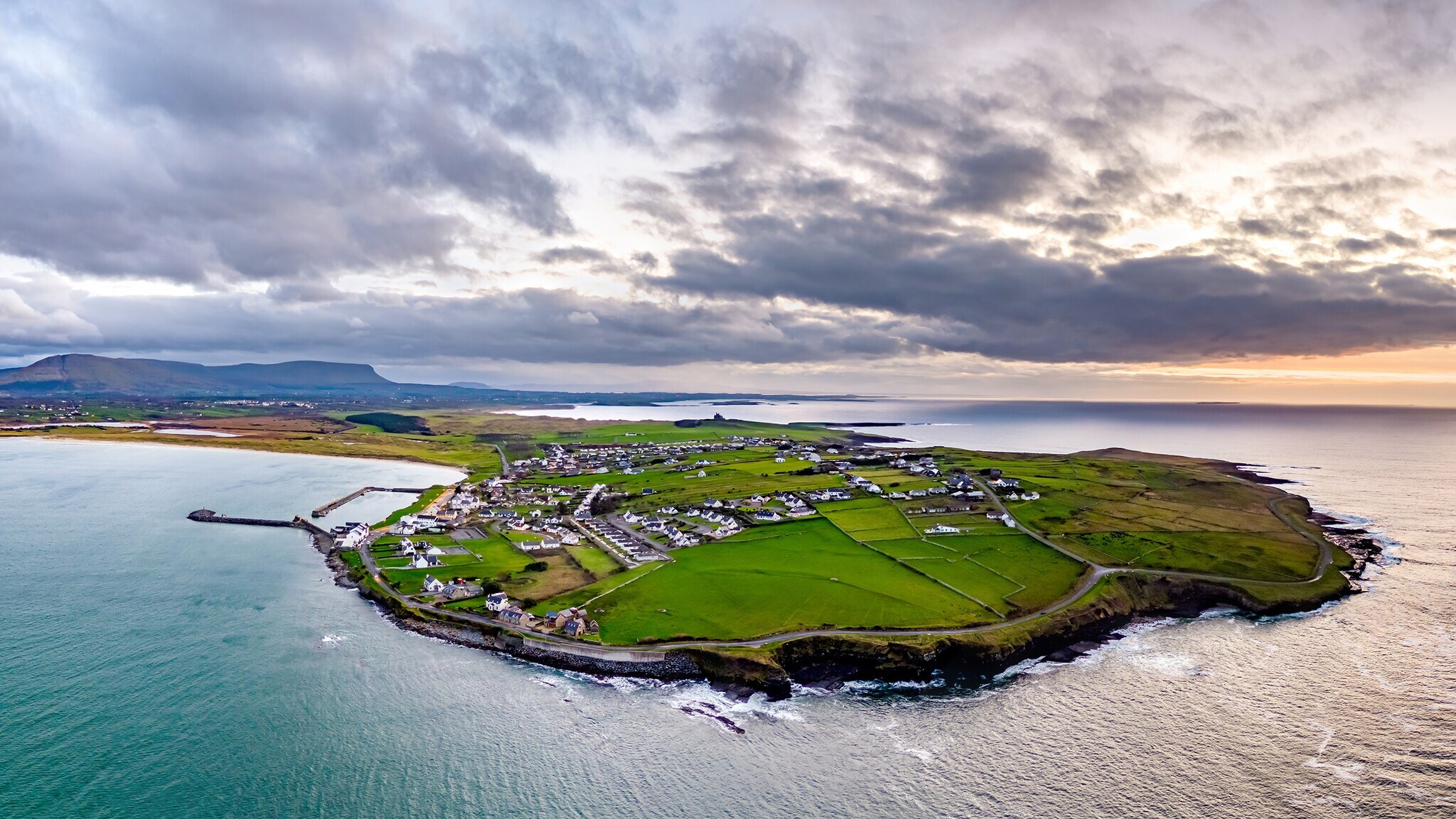 Luftaufnahme von einer grünen Halb-Insel mit kleinen Häuser, die von einem Meer umgeben ist. Luftaufnahme von einer grünen Halb-Insel mit kleinen Häuser, die von einem Meer umgeben ist.