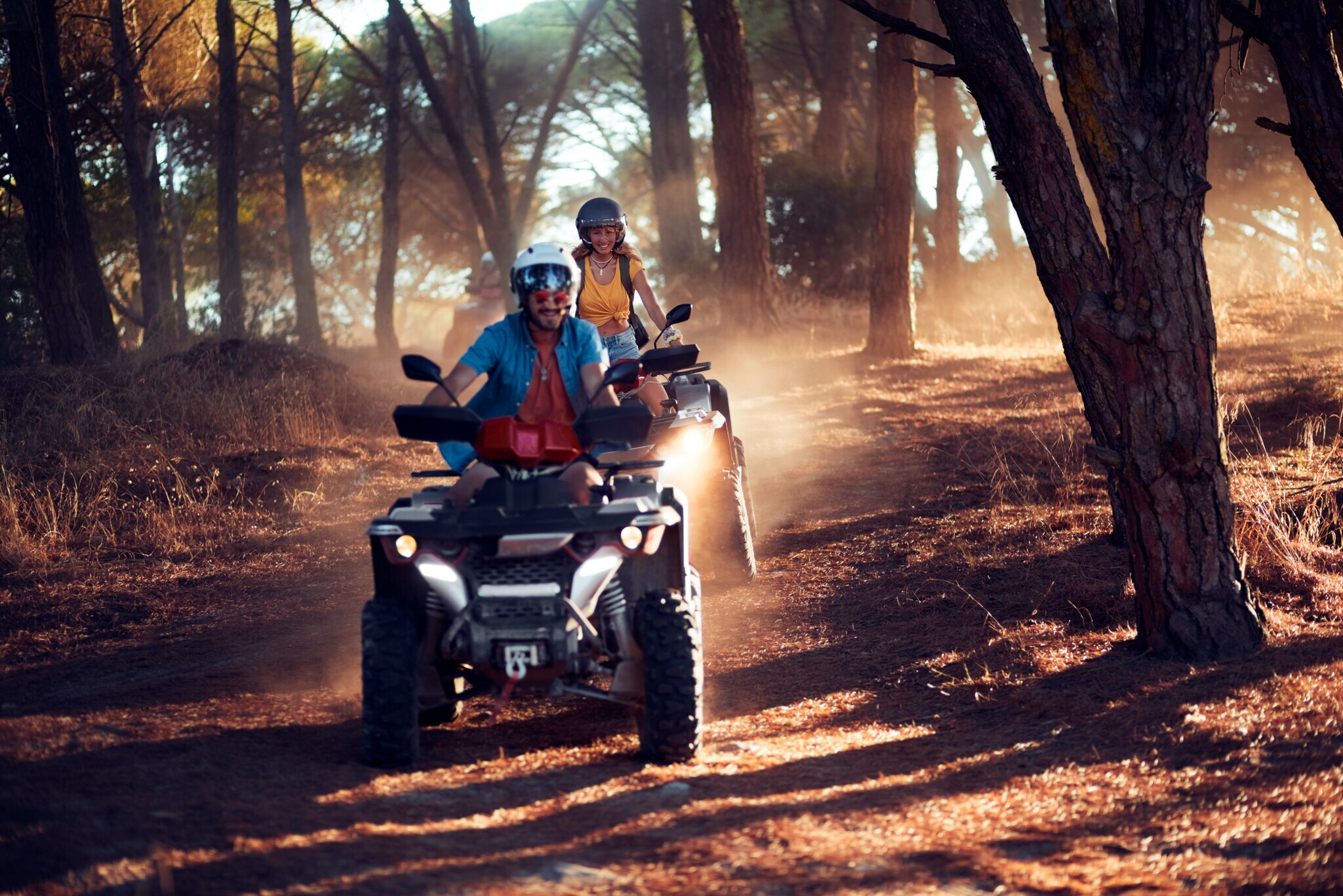 Ein Paar fährt auf zwei Quads gut gelaunt durch einen Wald