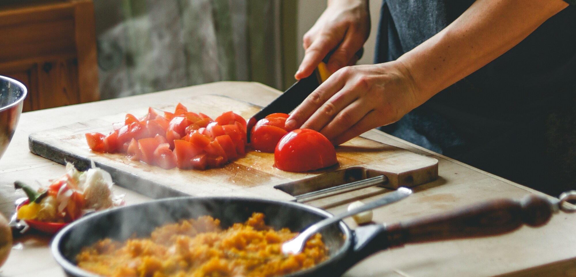 Ein Mann schneidet Tomaten und bereitet ein Gericht zu.