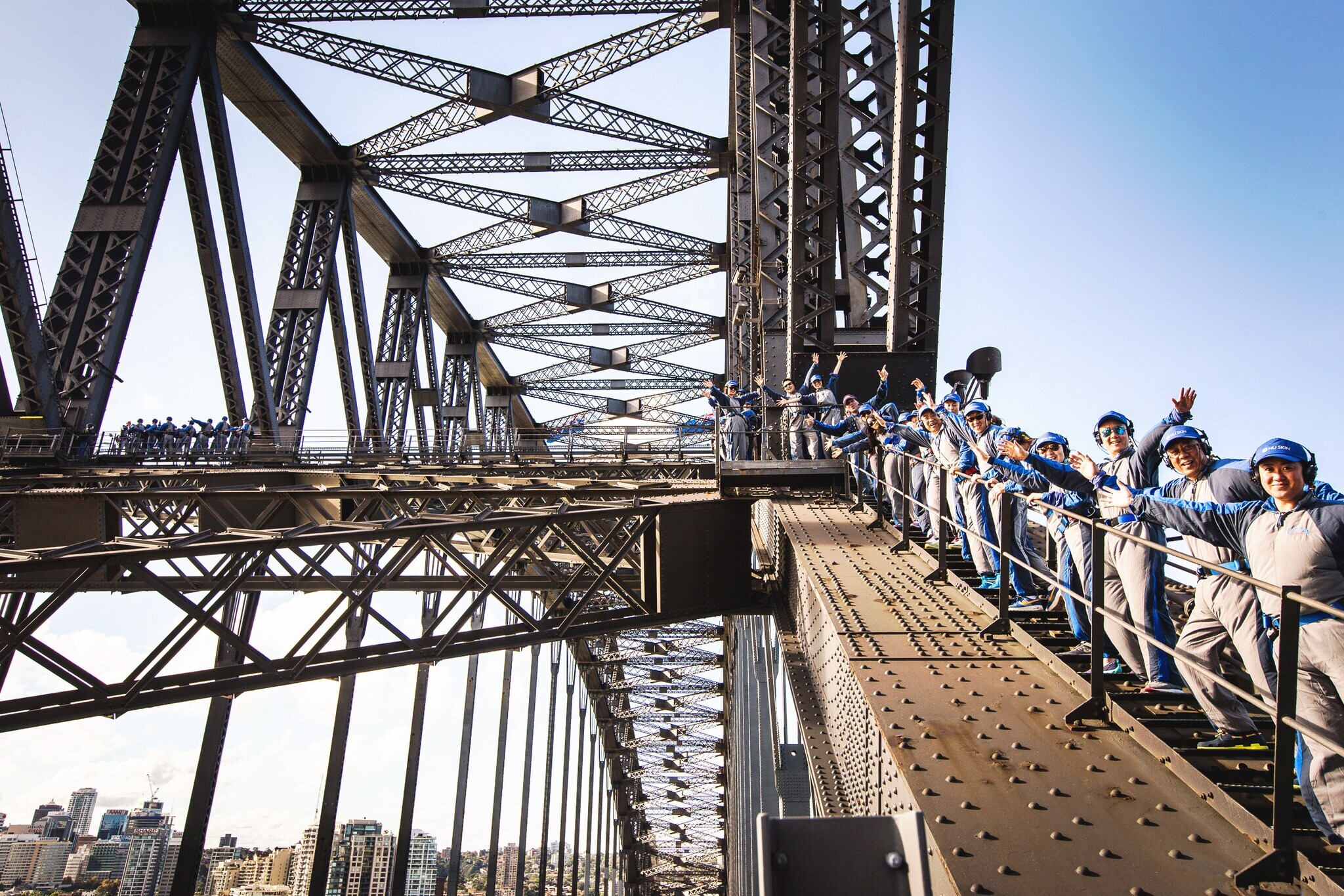 Männer und Frauen besteigen Sydneys Harbour Bridge und winken in die Kamera Männer und Frauen besteigen Sydneys Harbour Bridge und winken in die Kamera