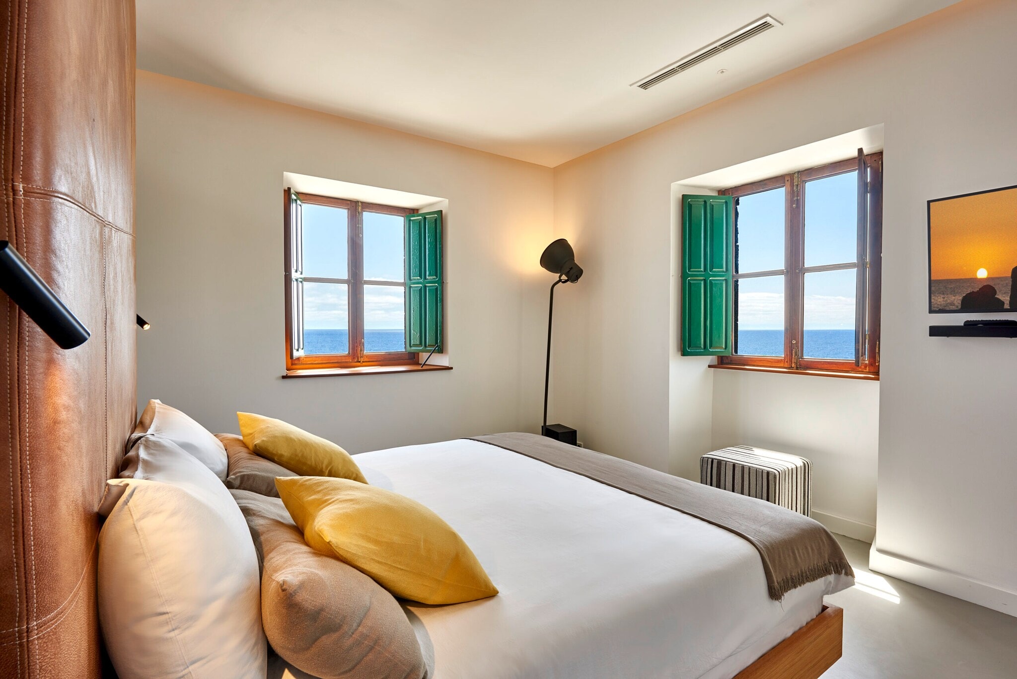 Eine stilvolle und schlichte Suite eines Leuchtturms, mit einer lederverkleideten Wand und heller Einrichtung Eine stilvolle und schlichte Suite eines Leuchtturms, mit einer lederverkleideten Wand und heller Einrichtung