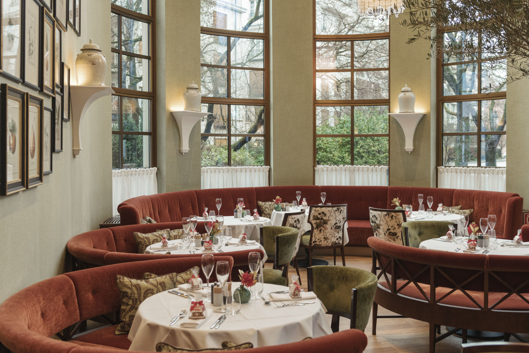 Schick gedeckte runde Tische am Fenster vor farbigen runden Polsterbänken in mediterranem Ambiente. Schick gedeckte runde Tische am Fenster vor farbigen runden Polsterbänken in mediterranem Ambiente.
