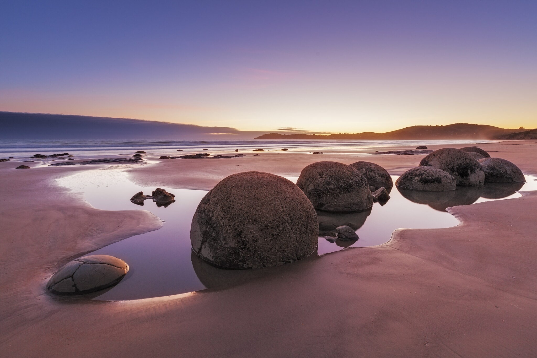 Große Steinkugeln am Strand, im Hintergrund geht die Sonne unter Große Steinkugeln am Strand, im Hintergrund geht die Sonne unter