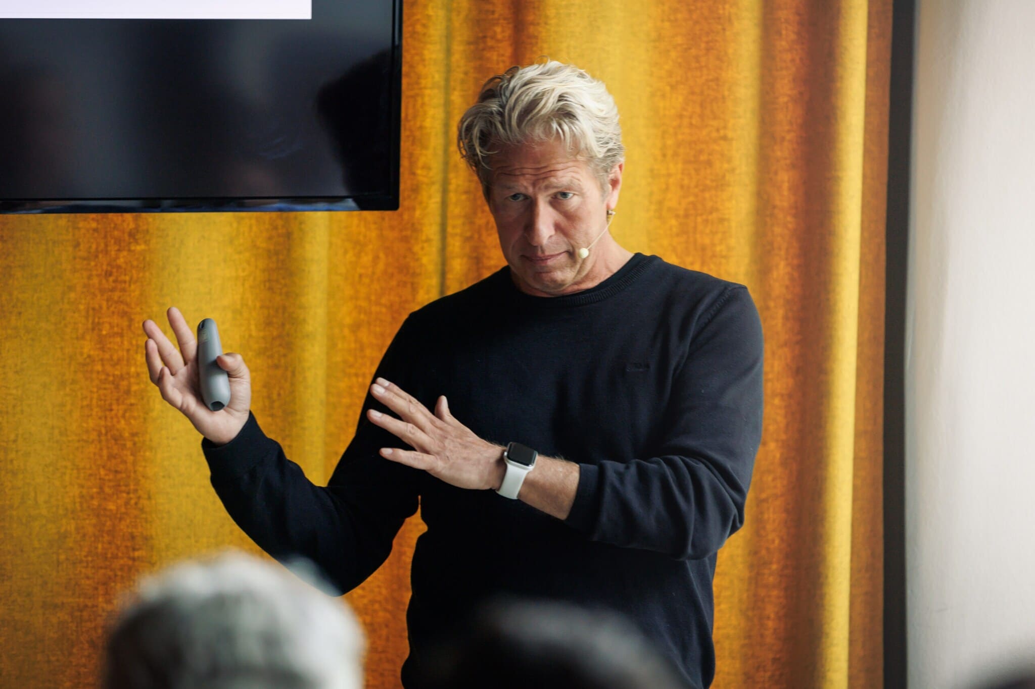 Oliver Leisse – Portrait Oliver Leisse steht vor einer Gruppe von Menschen und hält einen Vortrag.