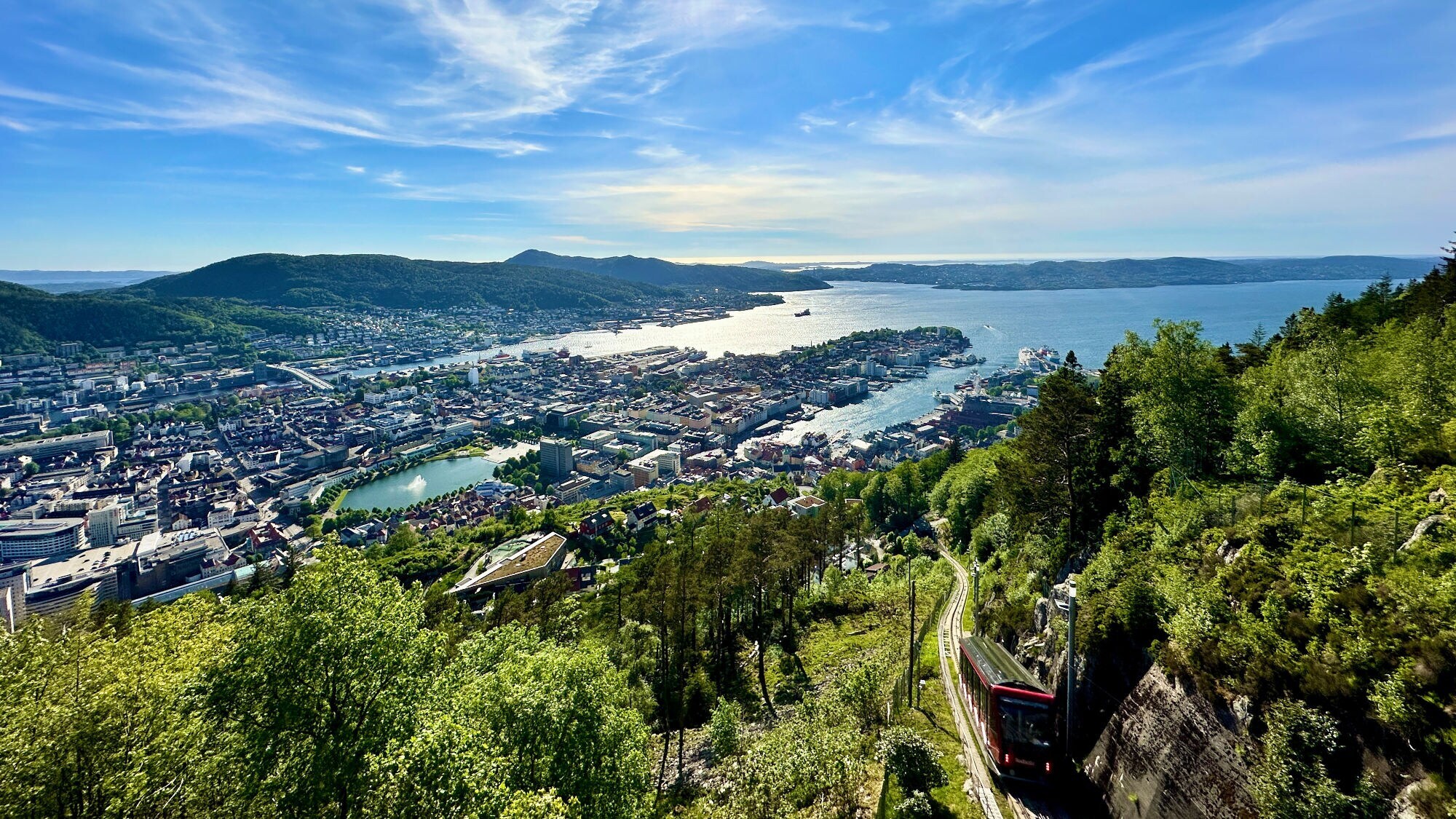 Luftaufnahme der Stadt Bergen in Norwegen mit Hafen, Stadt und Bergen unter blauem Himmel mit Sonne.