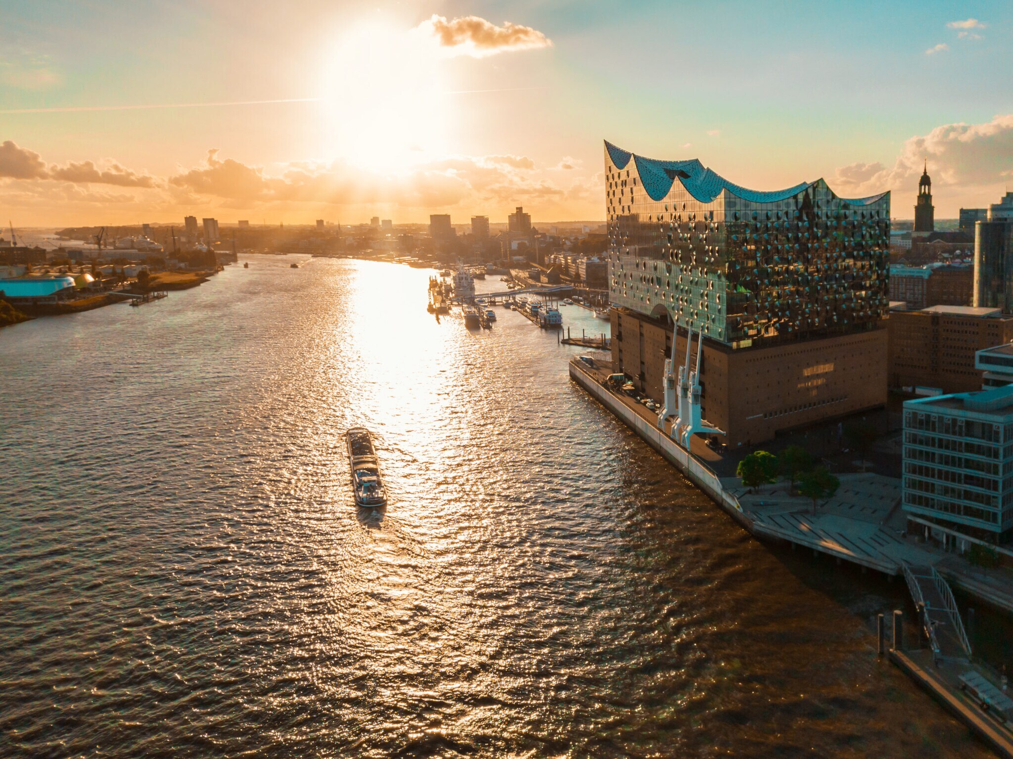Sonnenuntergang über der Elbphilharmonie in Hamburg mit einem Schiff auf der Elbe der Stadt im Hintergrund. Sonnenuntergang über der Elbphilharmonie in Hamburg mit einem Schiff auf der Elbe der Stadt im Hintergrund.