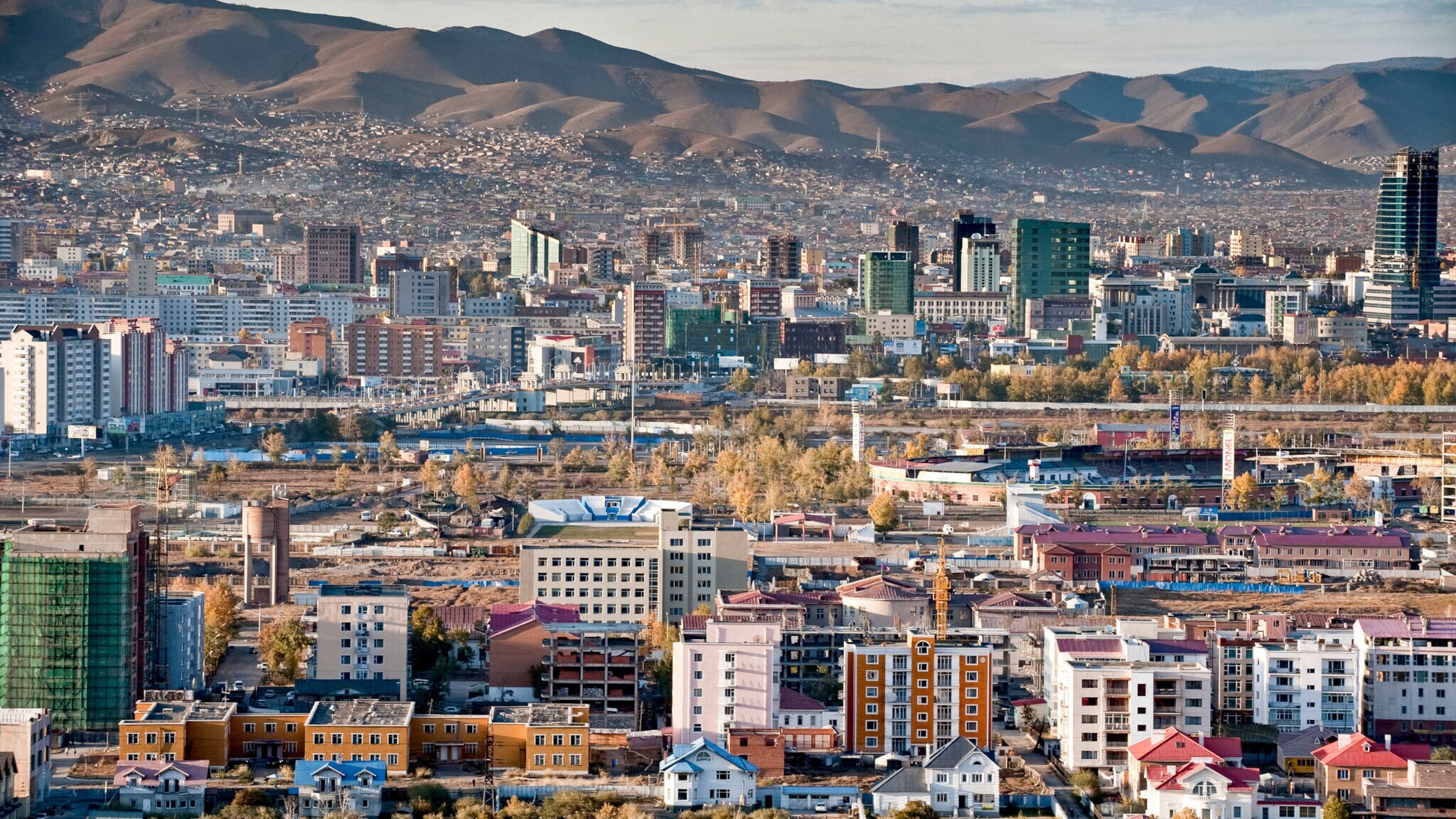 Fernaufnahme der Häuser von Ulaanbataar, der Hauptstadt der Mongolei, mit Gebirge im Hintergrund.
