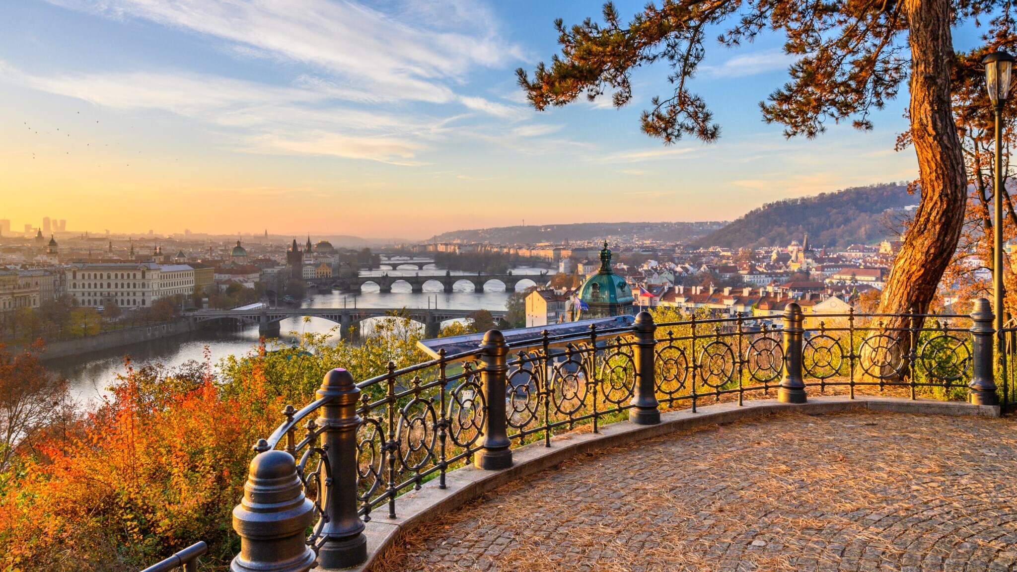 Blick auf die Moldau mit mehreren Brücken und der Altstadt von Prag im Sonnenuntergang, von einer Aussichtsplattform mit schmiedeeisernem Geländer Blick auf die Moldau mit mehreren Brücken und der Altstadt von Prag im Sonnenuntergang, von einer Aussichtsplattform mit schmiedeeisernem Geländer