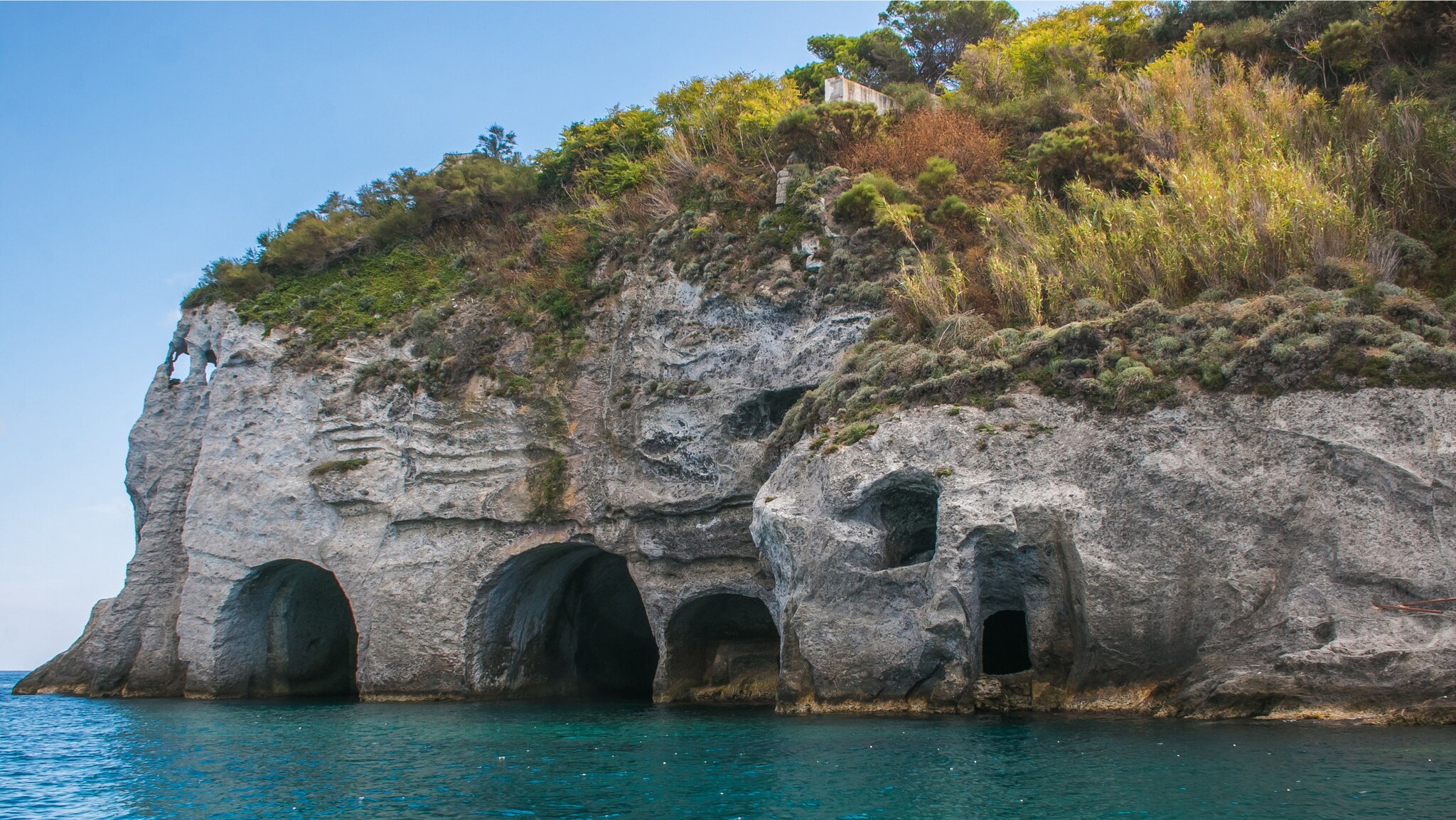 Meereshöhlen in einer steilen Felswand an der Küste von Ponza.