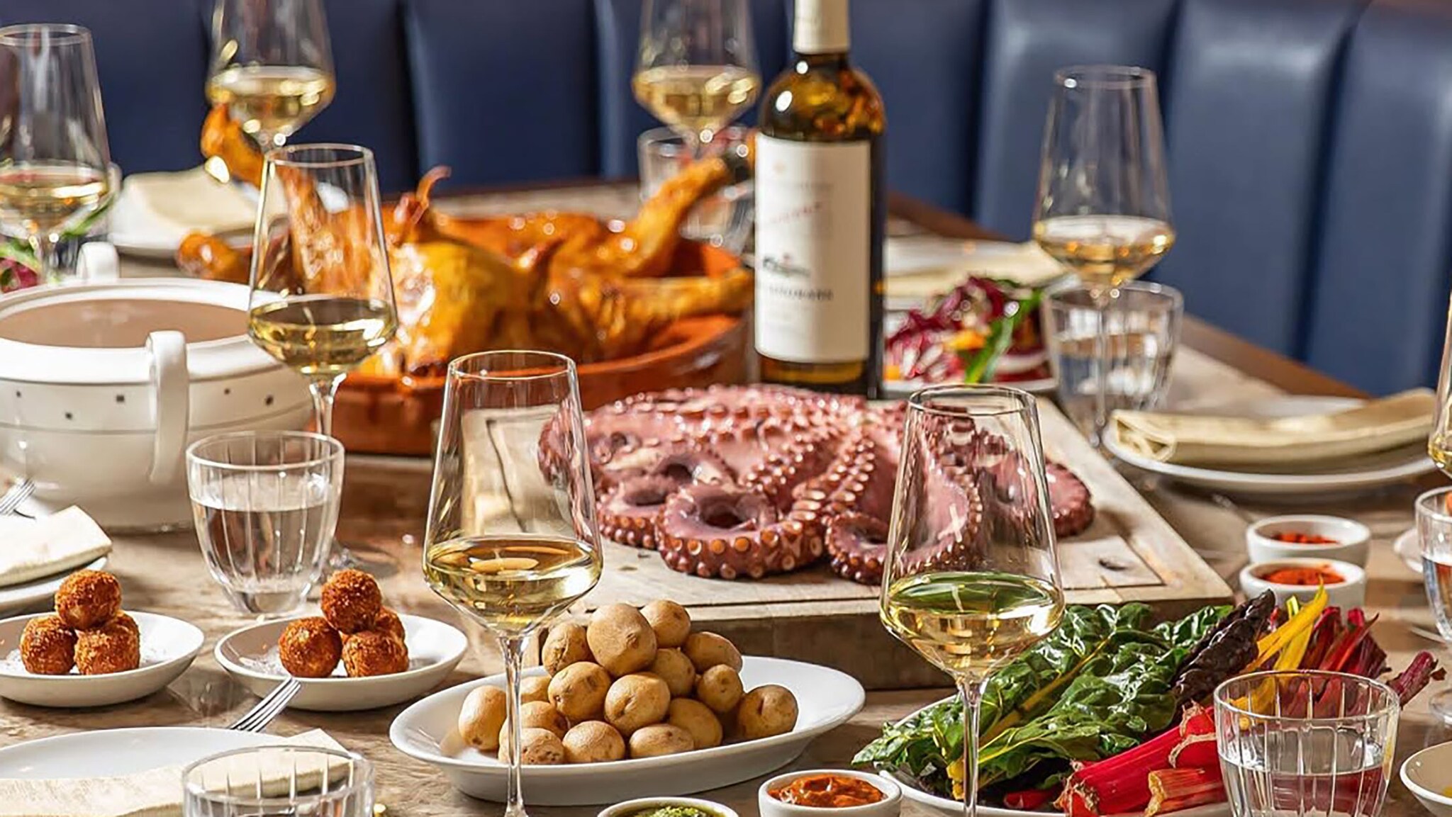 Restauranttisch mit Tapasgerichten und Tintenfisch mit Weingläsern.