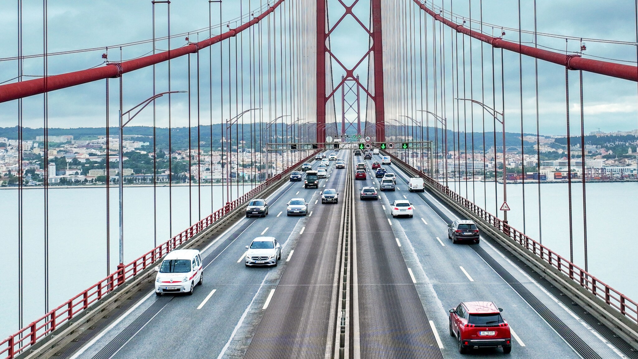 Sechsspurige Straße mit Autos auf einer roten Hängebrücke über einem Fluss. Sechsspurige Straße mit Autos auf einer roten Hängebrücke über einem Fluss.