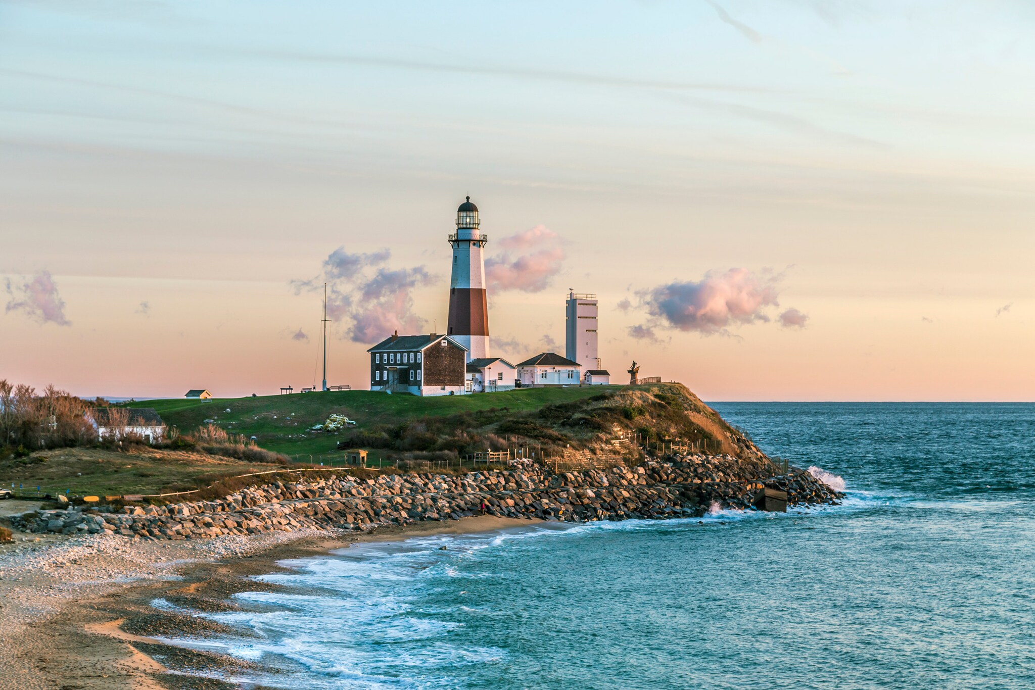 Ein rot-weißer Leuchtturm an einem Felsvorsprung am Meer.