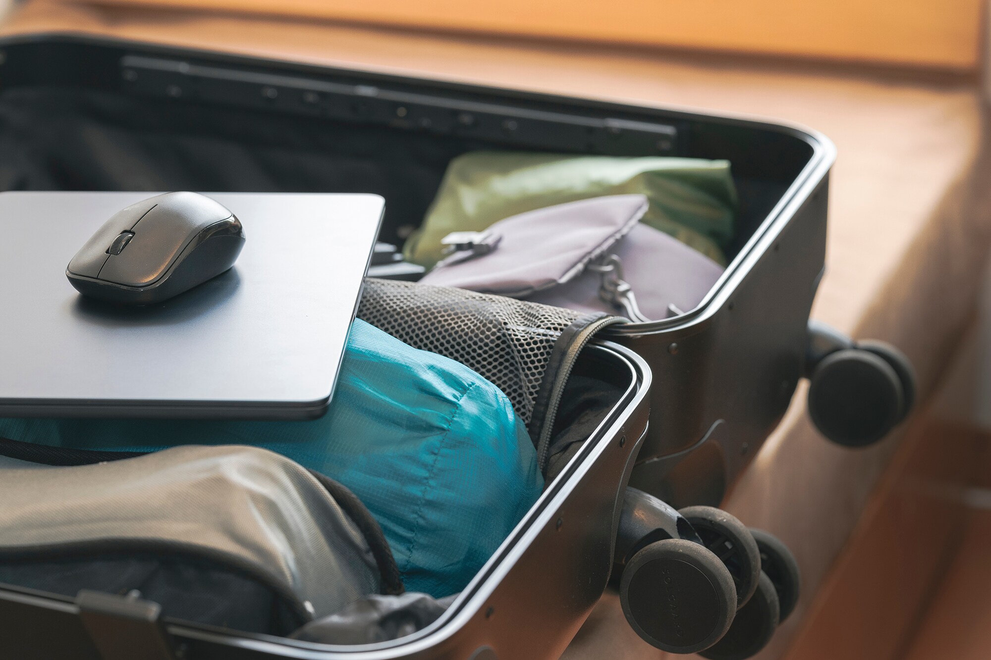 Das American Express Reisestellenkonto: Geschäftsreisen locker managen Laptop und Maus liegen in einem geöffneten Reisekoffer.