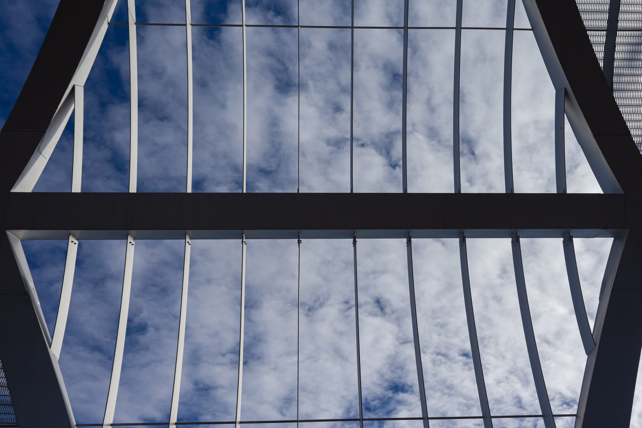 Abstraktes Foto paralleler Metallverstrebungen vor bewölktem Himmel