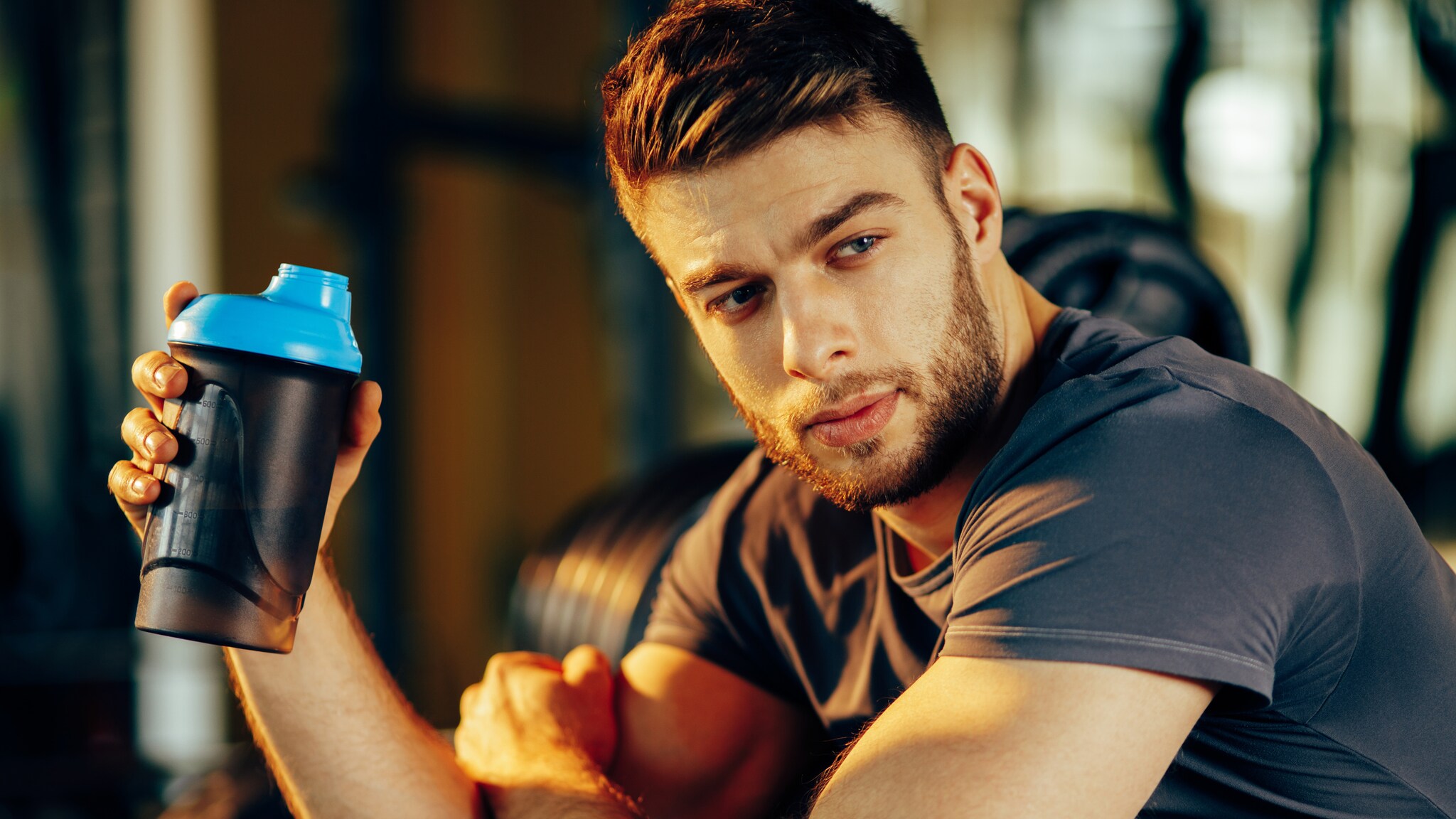 Ein Mann in Sportkleidung hält einen Protein-Shaker in der Hand. Ein Mann in Sportkleidung hält einen Protein-Shaker in der Hand.