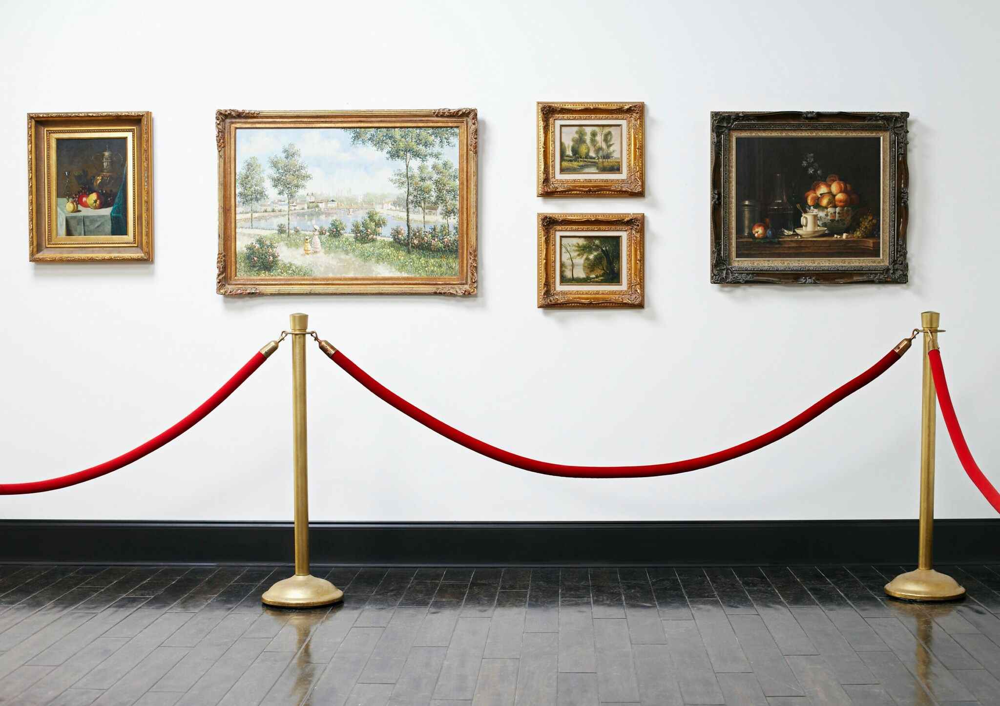 Vier Ölgemälde mit Antikrahmen an der Wand, davor ein Absperrseil
