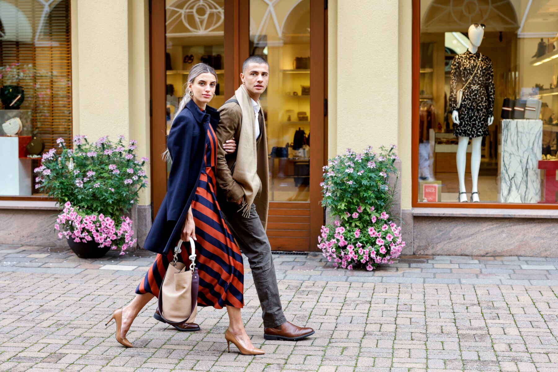 Ein junges Paar geht Arm in Arm durch eine Einkaufsstraße Ein junges Paar geht Arm in Arm durch eine Einkaufsstraße