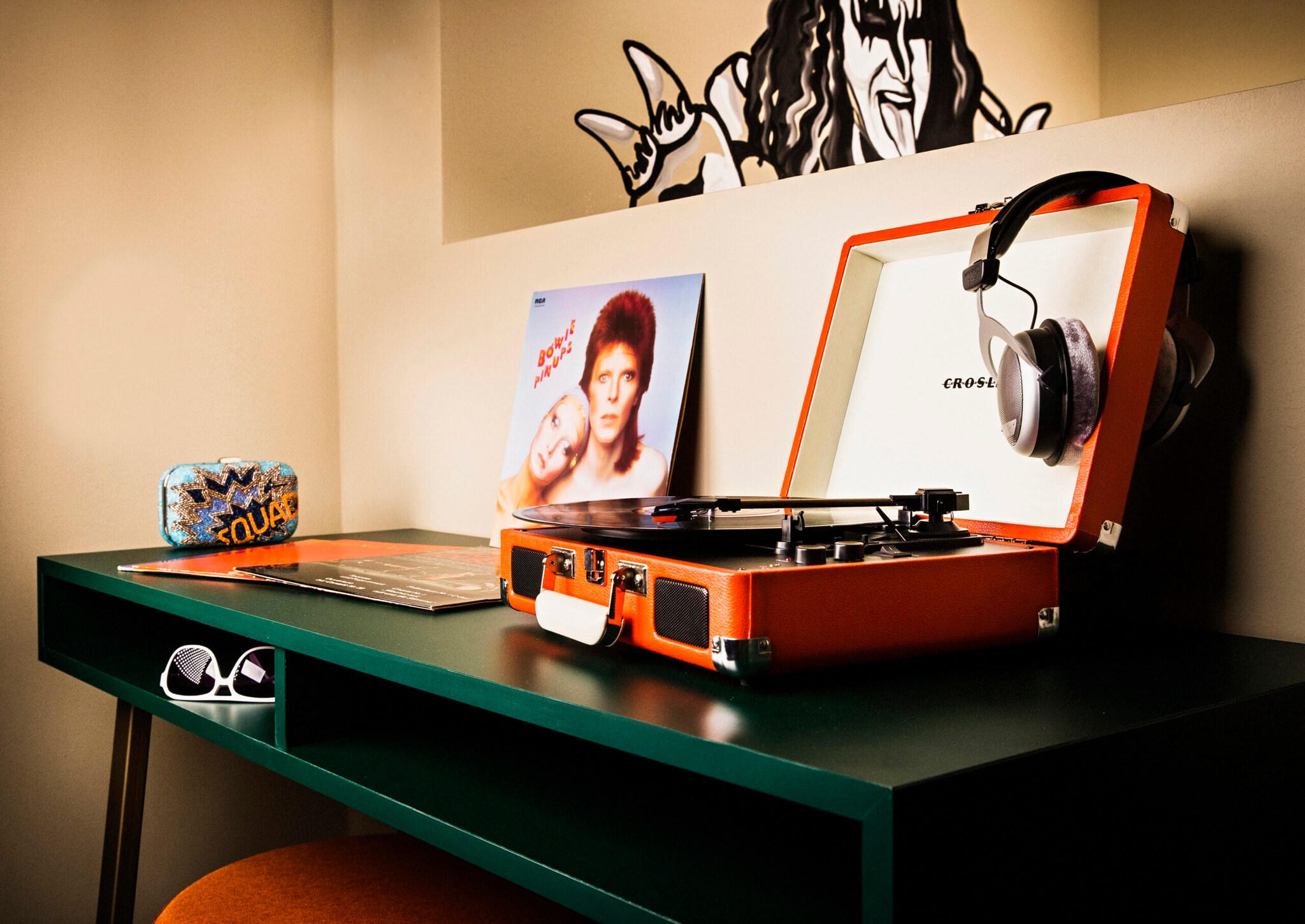 Ein Grüner Tisch mit portablem Plattenspieler und einer David Bowie Schallplatte danaben Ein Grüner Tisch mit portablem Plattenspieler und einer David Bowie Schallplatte danaben