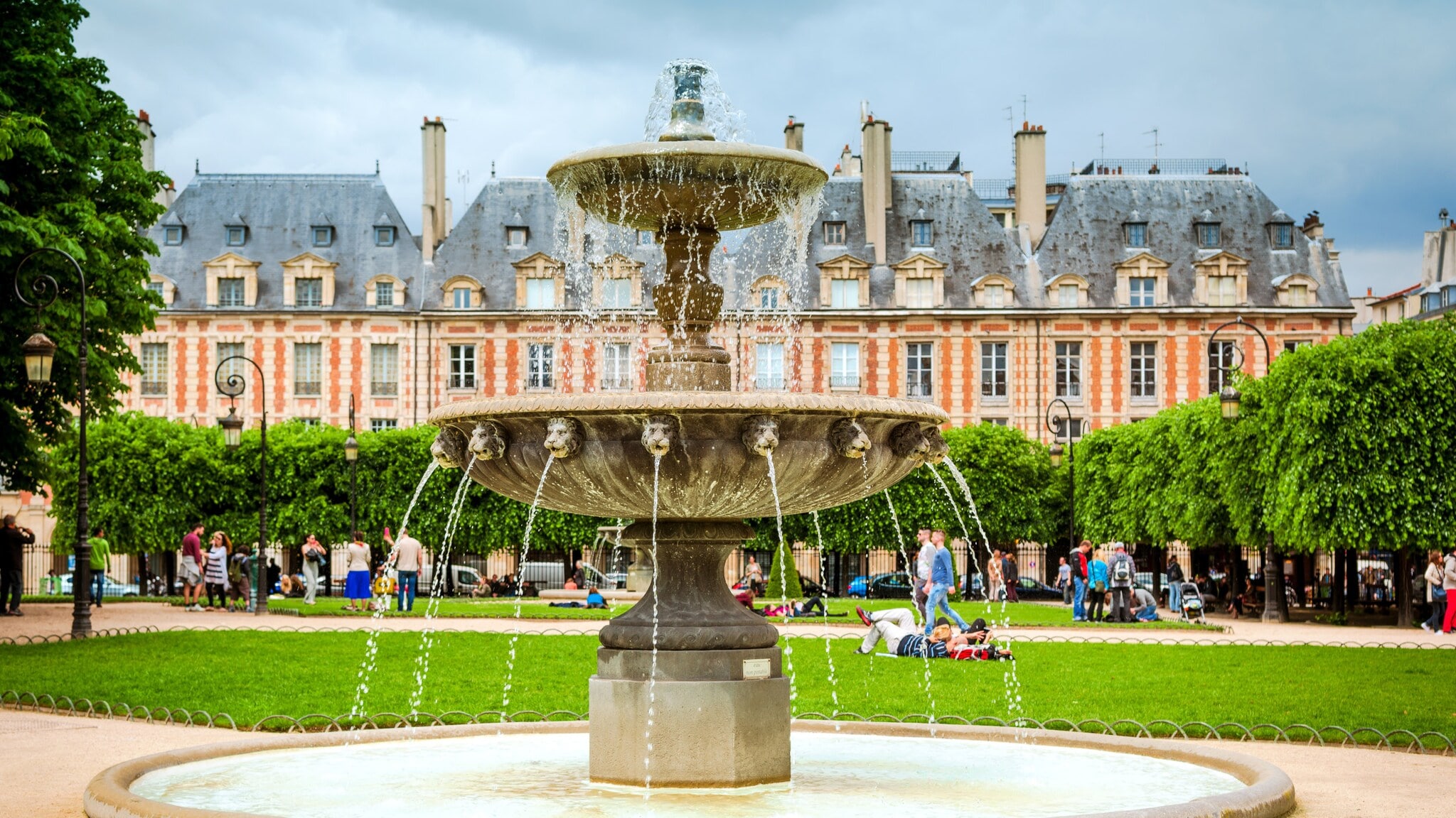 Brunnen mit fließendem Wasser im Place des Vosges, Paris, vor historischen Gebäuden und Bäumen Brunnen mit fließendem Wasser im Place des Vosges, Paris, vor historischen Gebäuden und Bäumen