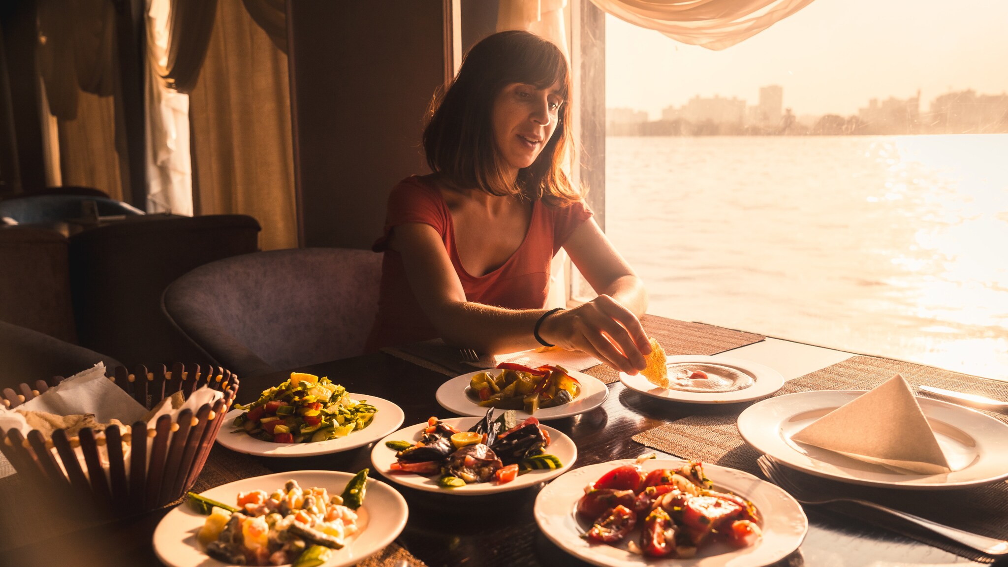 Eine Frau an einem Tisch dippt Brot in ein Gericht auf einem von mehreren Tellern.