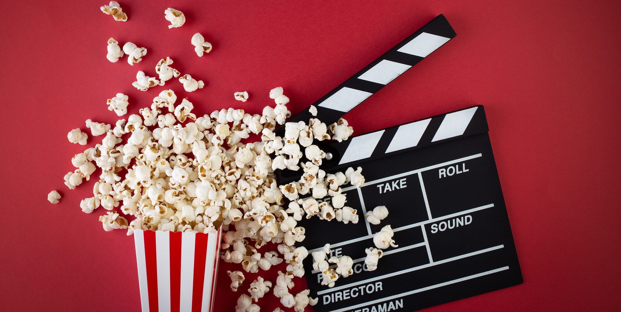 Popcorn und eine Filmklappe vor rotem Hintergrund Popcorn und eine Filmklappe vor rotem Hintergrund