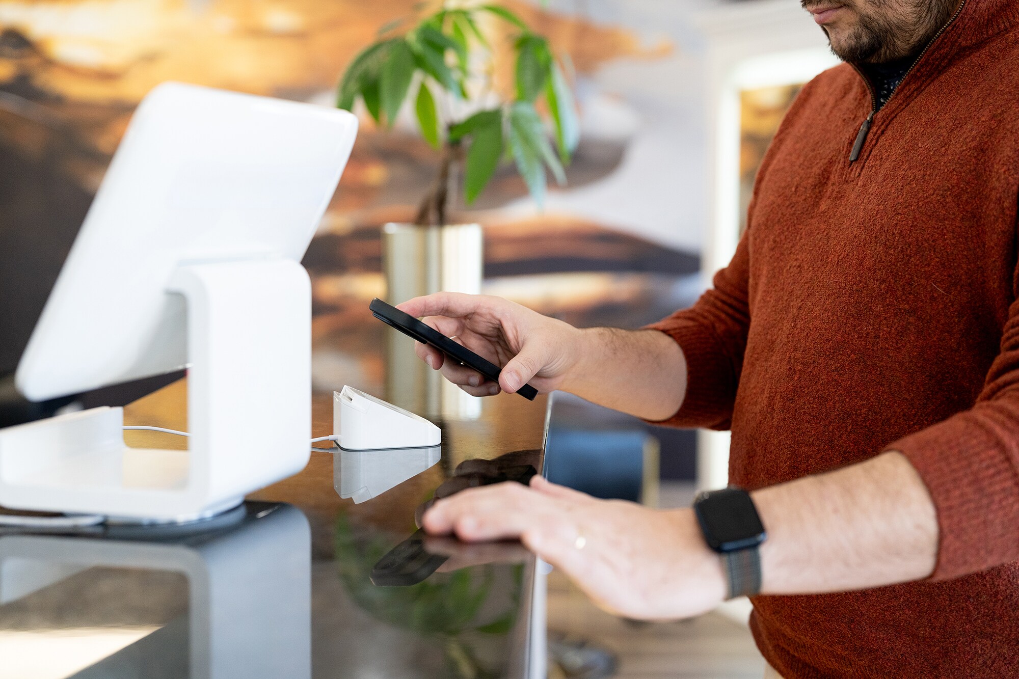 Nahaufnahme eines Mannes, der via Smartphone eine Zahlung in einem Geschäft tätigt.