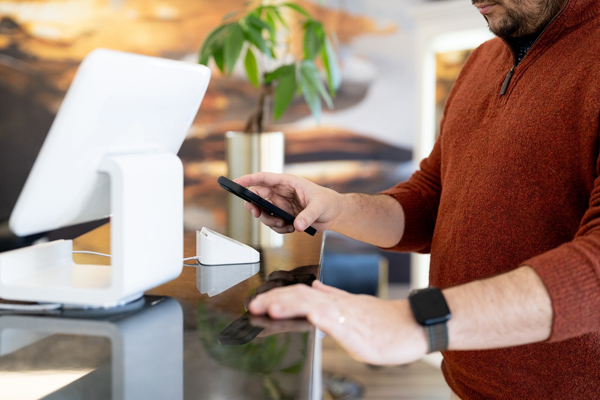 Mobiles Bezahlen: Wie die Zukunft des Check-outs dein Business verändert Nahaufnahme eines Mannes, der via Smartphone eine Zahlung in einem Geschäft tätigt.