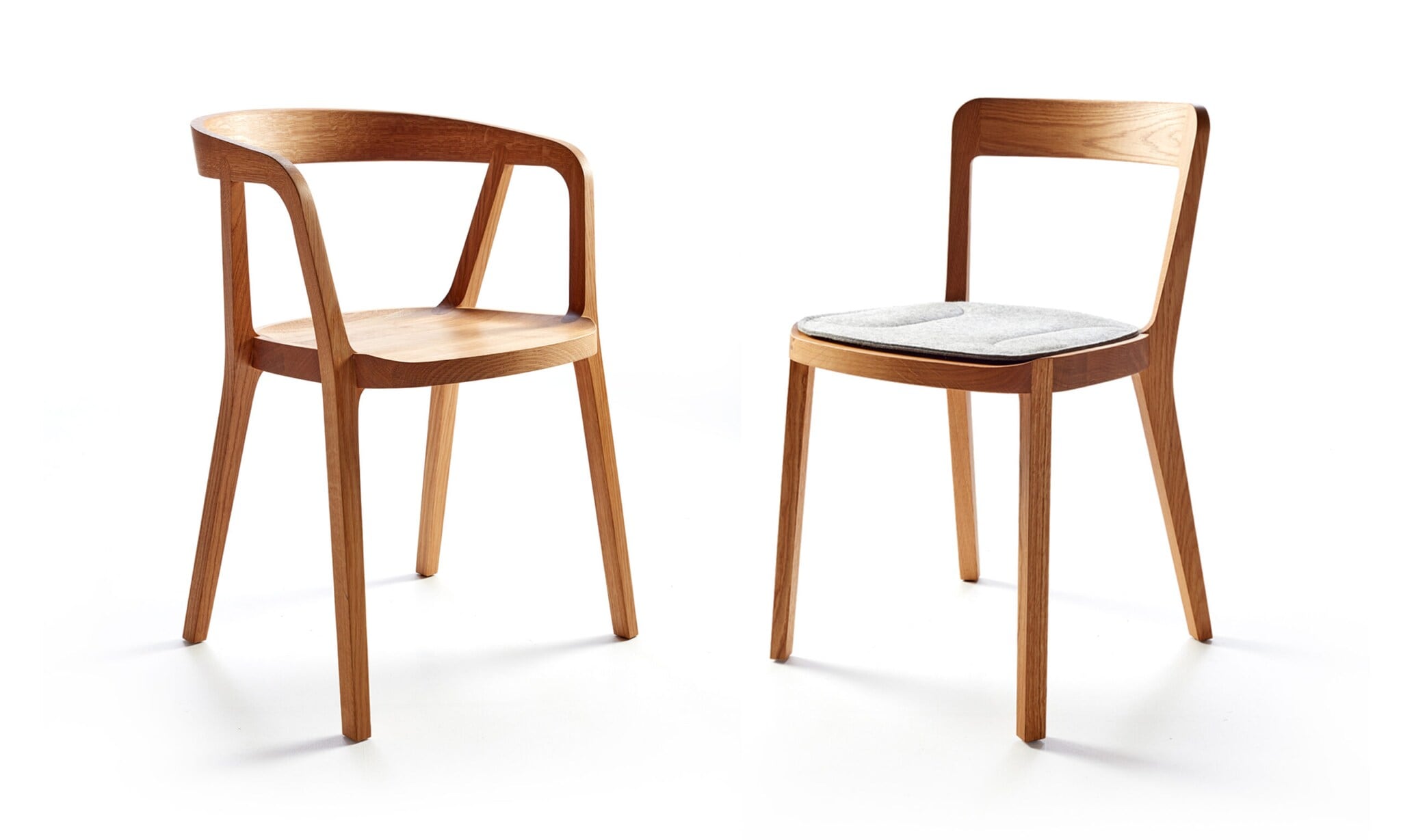 Zwei ergonomisch geformte Esstischstühle aus hellem Massivholz Zwei ergonomisch geformte Esstischstühle aus hellem Massivholz