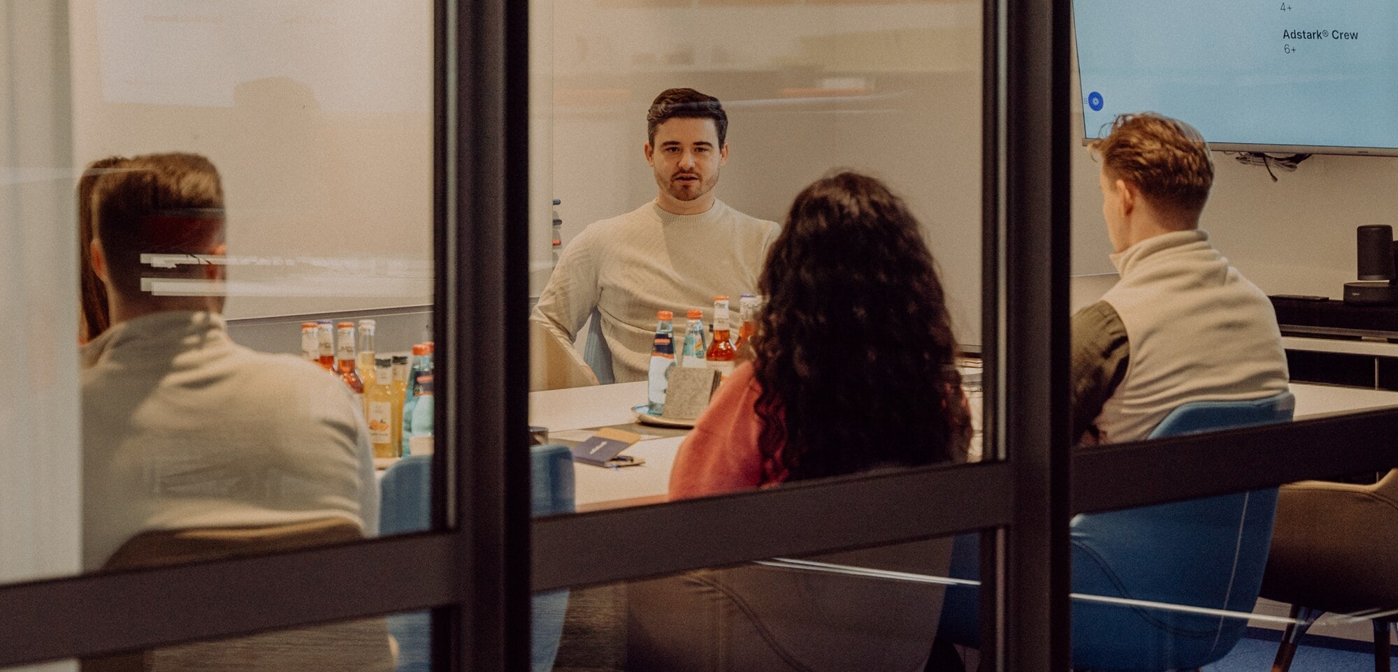 Strukturiertes Onboarding: So gelingt der Quereinstieg. Eine Gruppe von Kolleg:innen sitzt in einem Besprechungsraum.