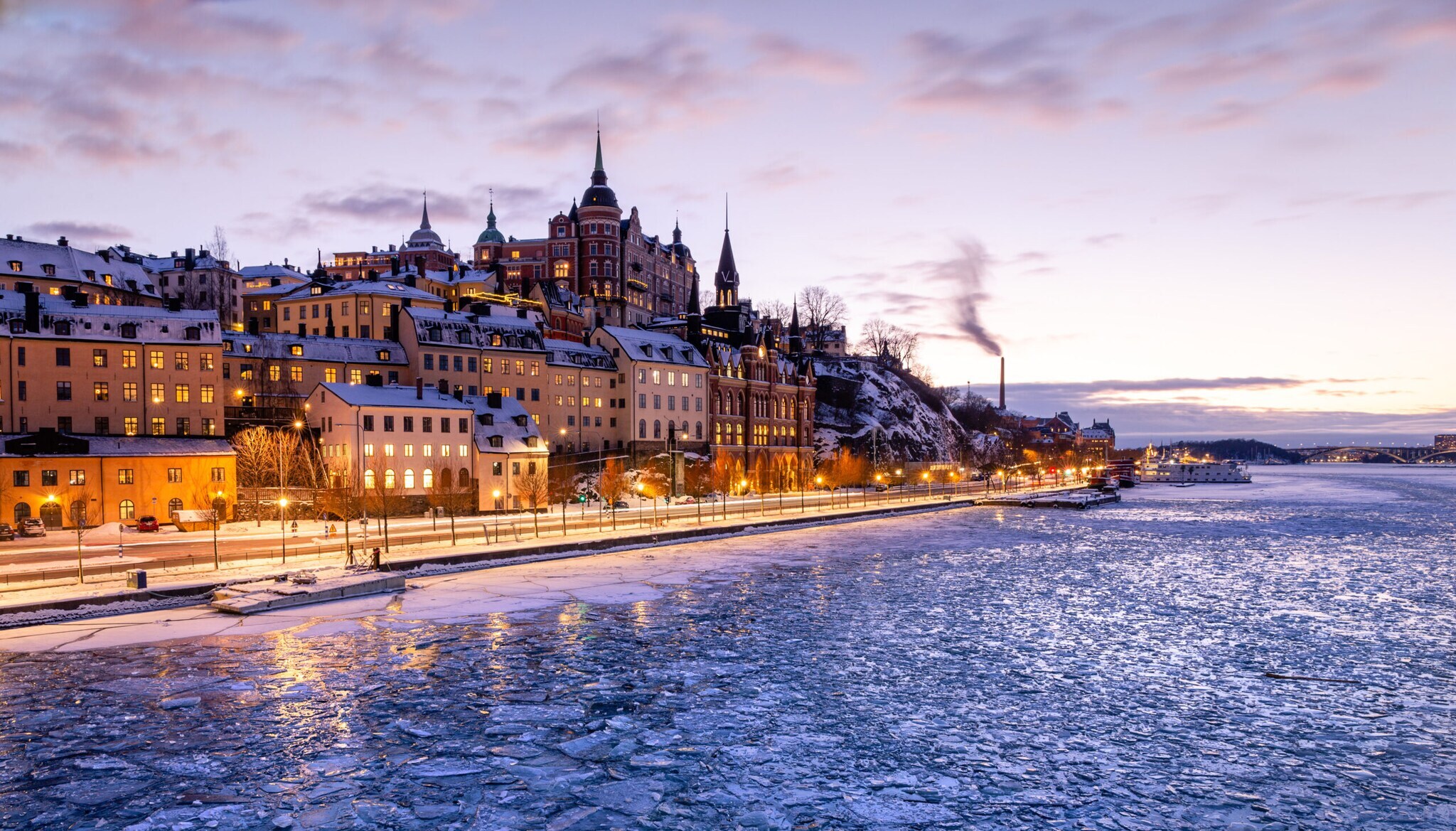 Ein Teil der pittoresken und eingeschneiten Insel Södermalm bei Dämmerung mit Eisschollen auf dem umliegenden Wasser