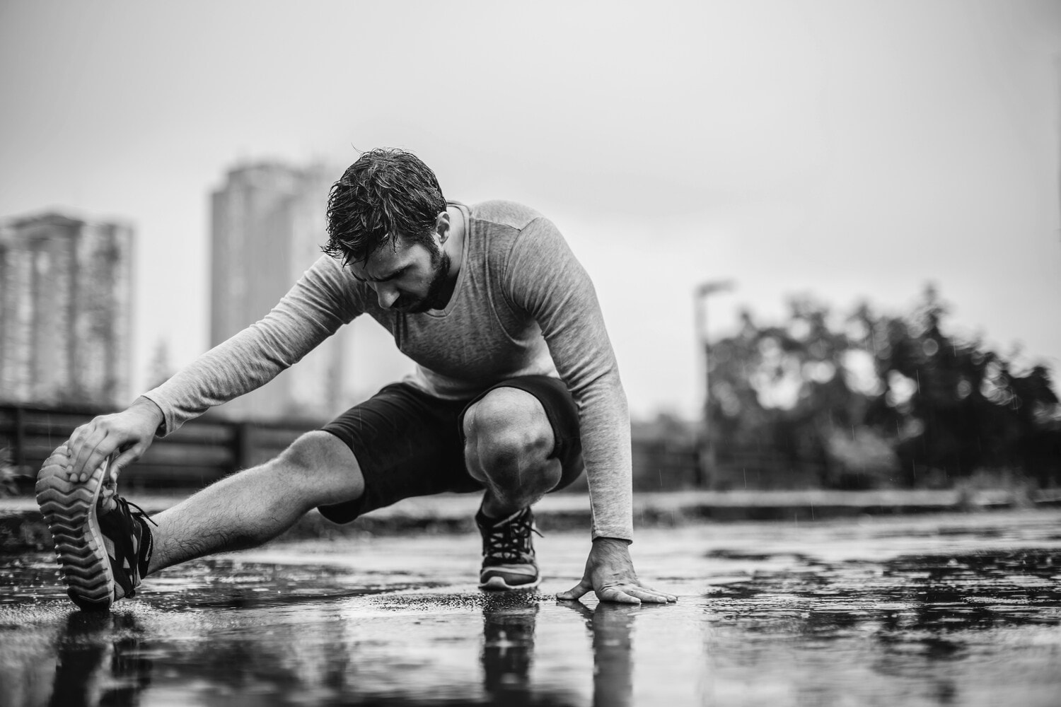 Schwarz-Weiß-Fotografie eines Mannes beim Stretchen Schwarz-Weiß-Fotografie eines Mannes beim Stretchen