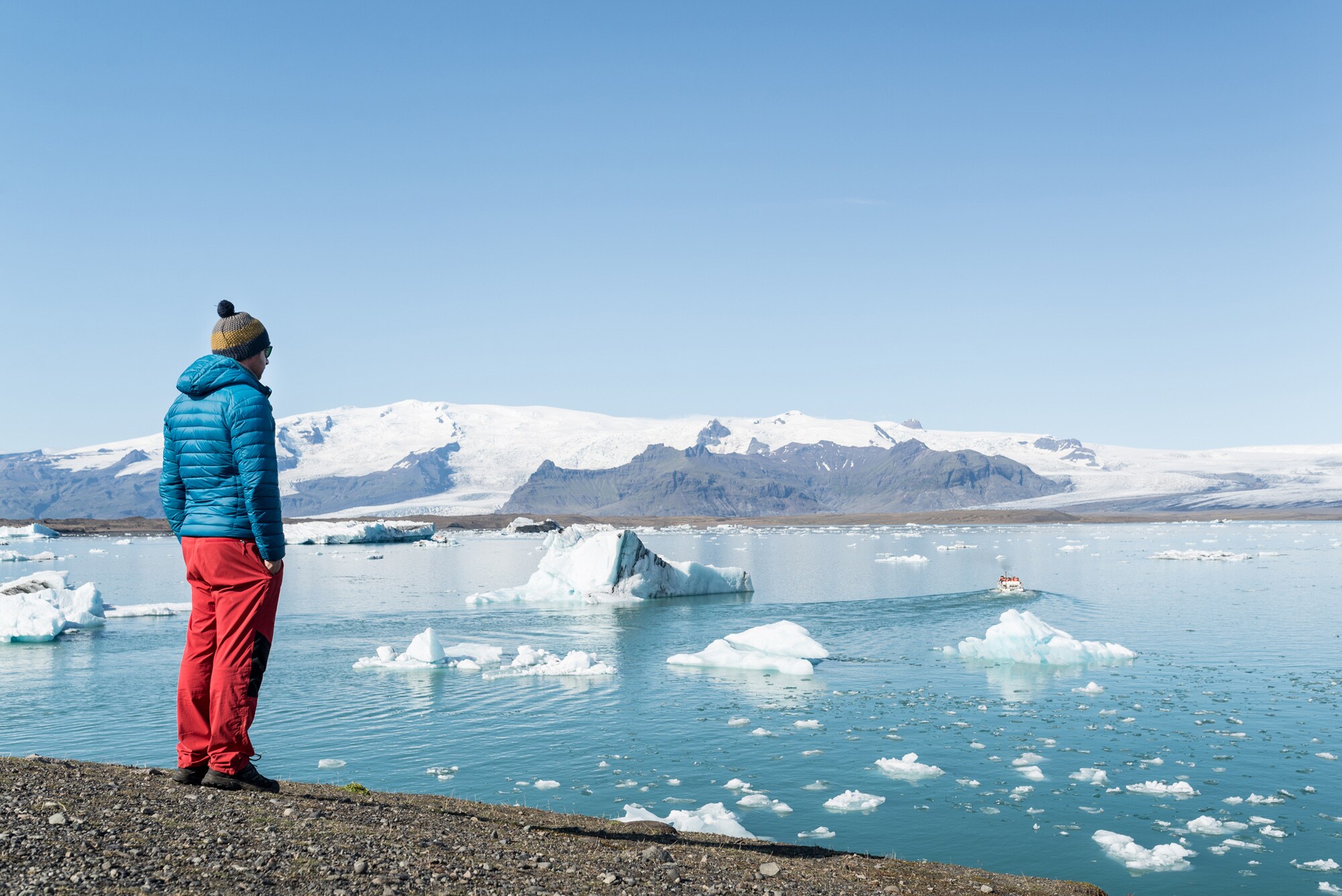 Eine Person blickt auf die Eisberge in der Gletscherlagune Jökulsárlón in Island.