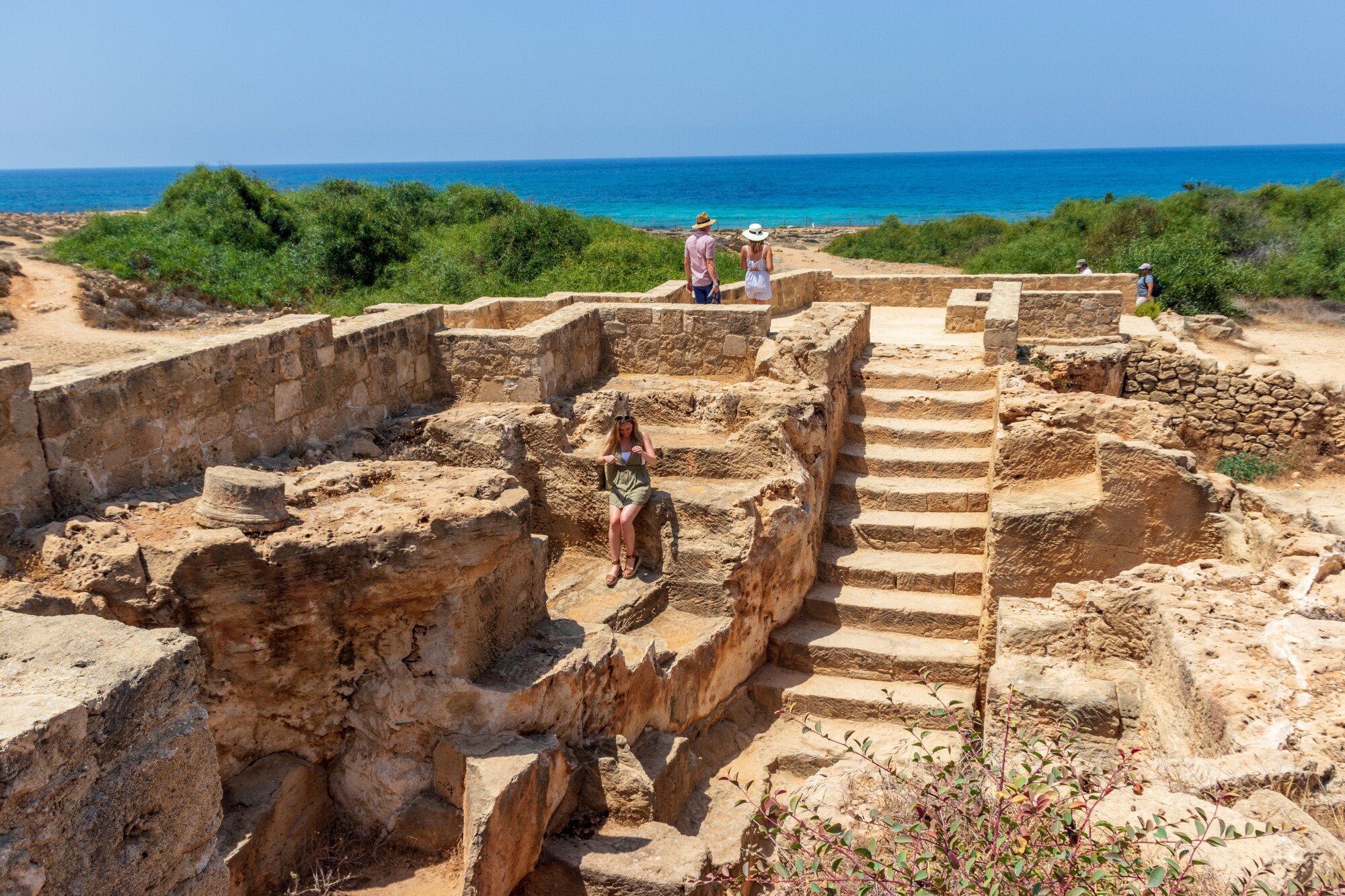 Personen in einer Ausgrabungsstätte am Meer.