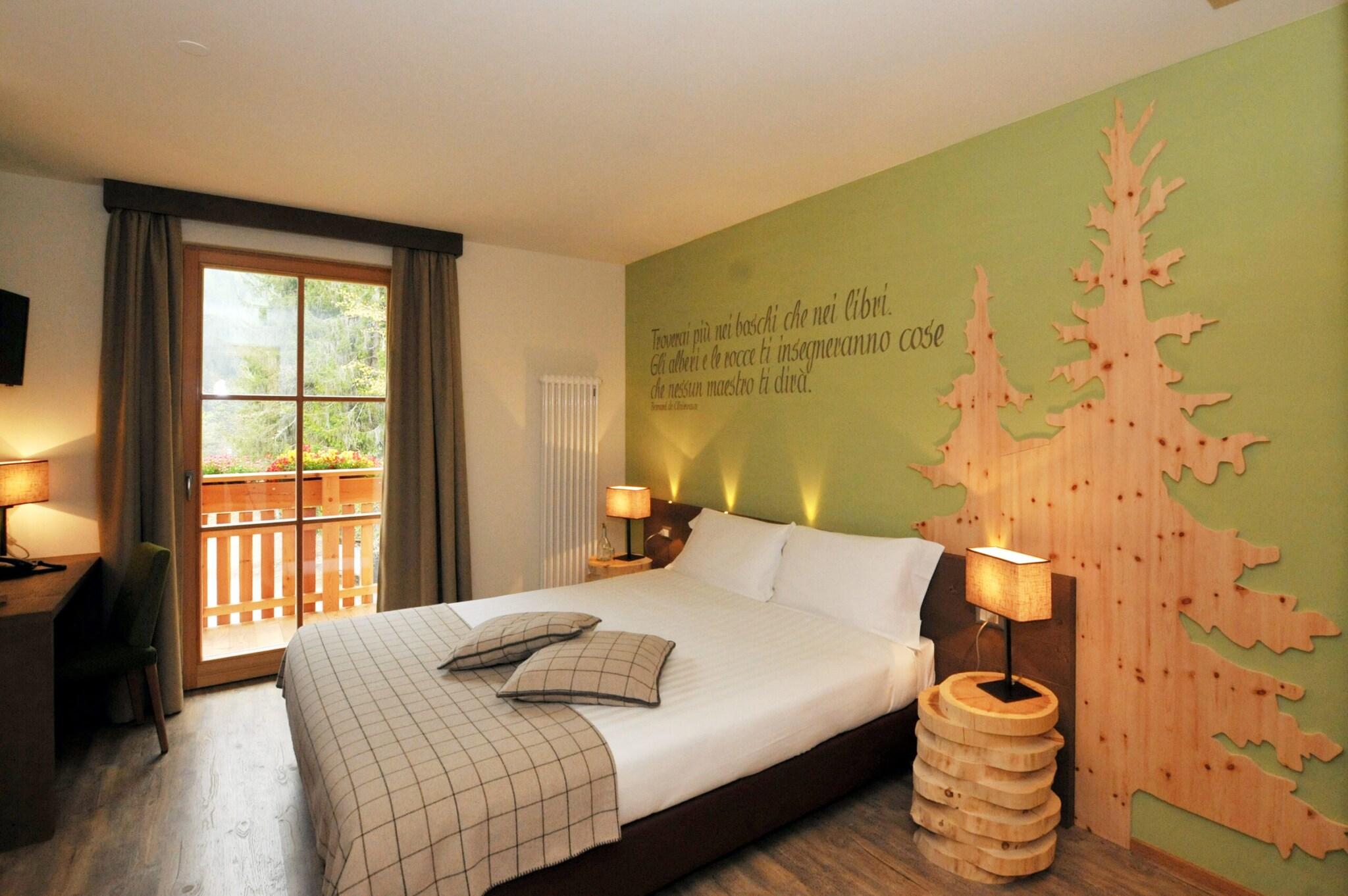 Ein Hotelzimmer mit Doppelbett, Dekorationselementen aus Holz und einem Balkon mit Blick ins Grüne