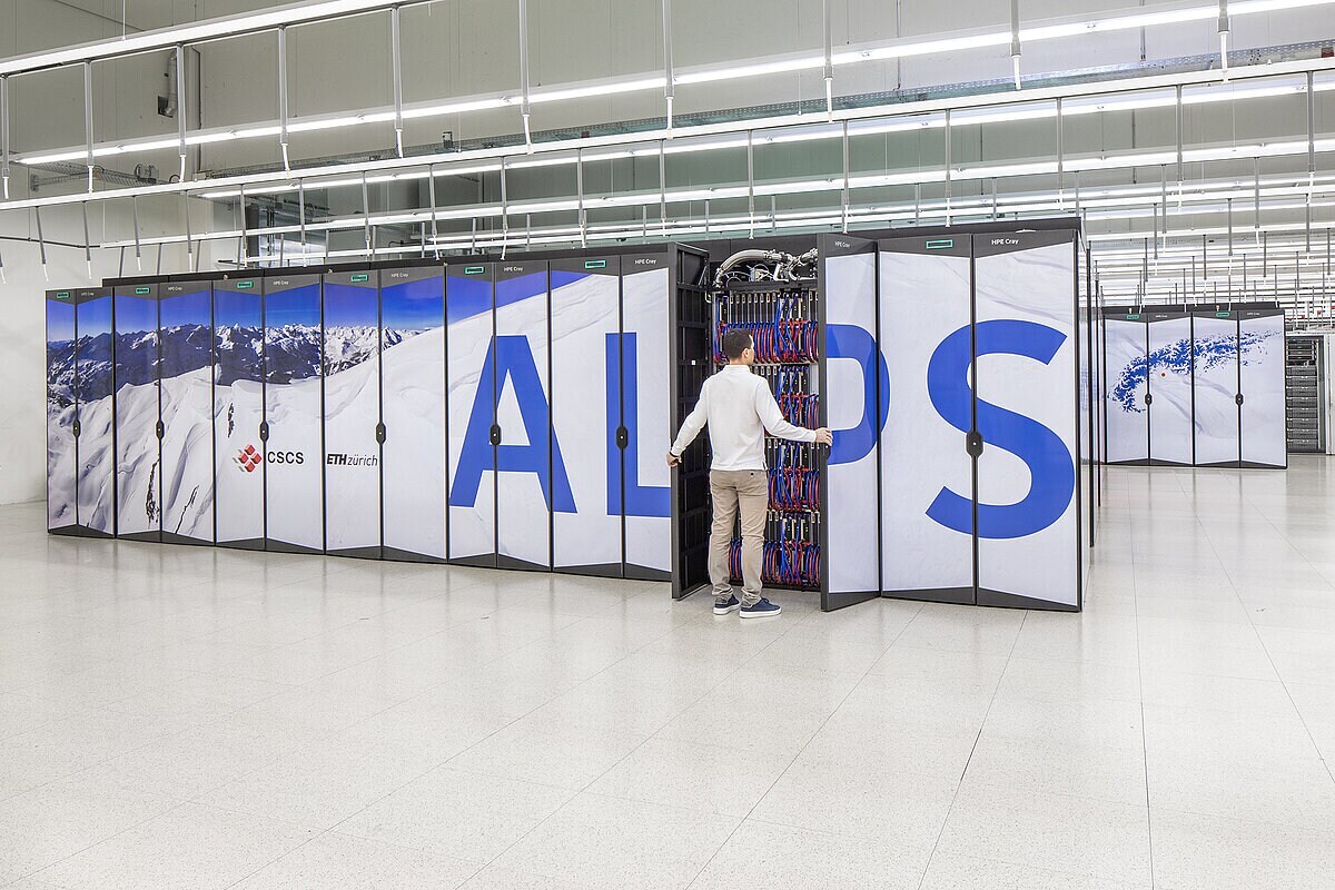 Ein Mann steht vor dem ALPS Supercomputer und betrachtet die Verkabelung. Ein Mann steht vor dem ALPS Supercomputer und betrachtet die Verkabelung.