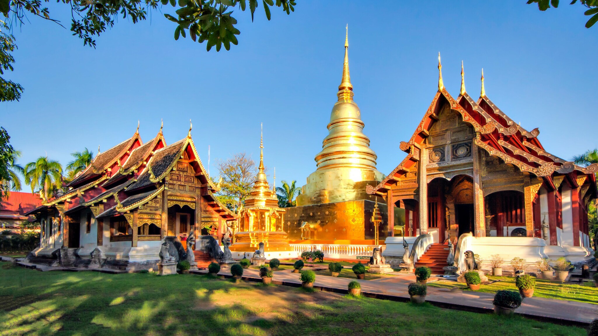 Buddhistische Tempelanlage mit goldenen Spitztürmen im warmen Sonnenlicht.
