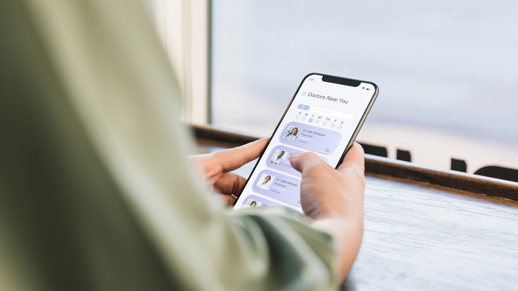 Eine Person hält ein Smartphone in der Hand und scrollt durch eine App mit Profilbildern und Namen. Auf dem Tisch steht ein Glas mit kaltem Kaffee. Eine Person hält ein Smartphone in der Hand und scrollt durch eine App mit Profilbildern und Namen. Auf dem Tisch steht ein Glas mit kaltem Kaffee.