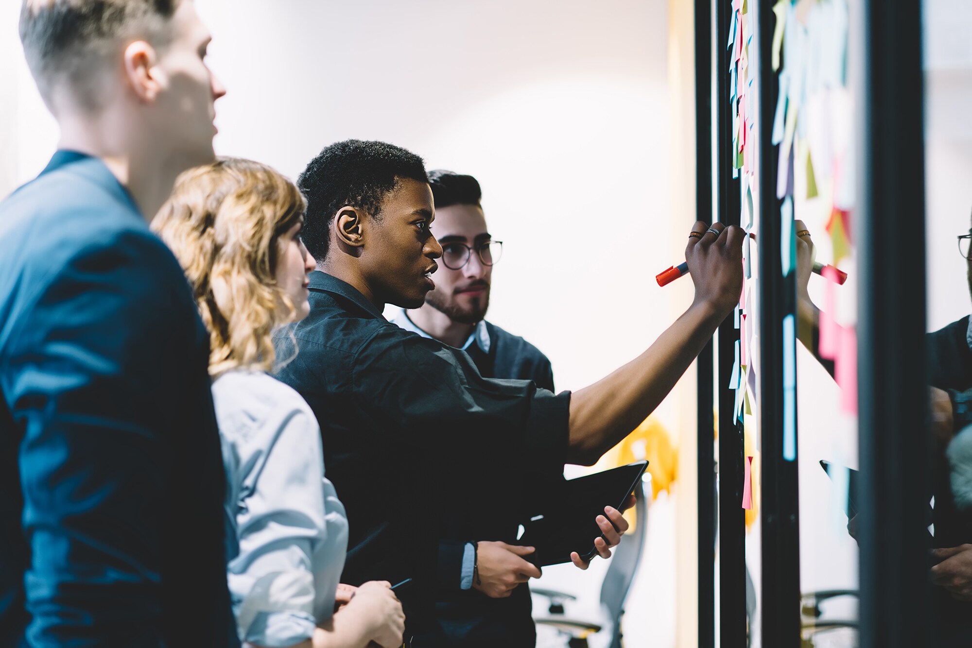 Purpose, please: Warum der Unternehmenszweck wichtiger ist als das Produkt Eine Gruppe von Kolleg:innen steht am Whiteboard und erarbeitet in einem Workshop die Frage nach dem Warum.