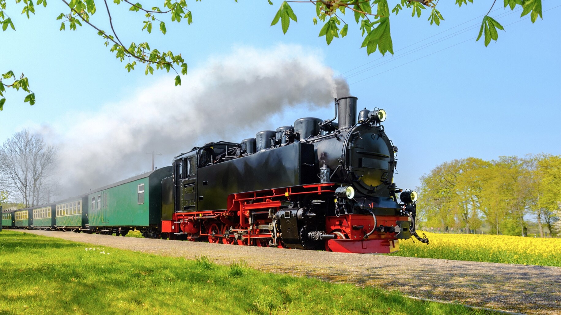 Dampflok mit schwarzem Kessel und rotem Rahmen zieht einen grünen Waggon auf dem Hindenburgdamm in Sylt. Rauch steigt aus dem Schornstein auf. Dampflok mit schwarzem Kessel und rotem Rahmen zieht einen grünen Waggon auf dem Hindenburgdamm in Sylt. Rauch steigt aus dem Schornstein auf.