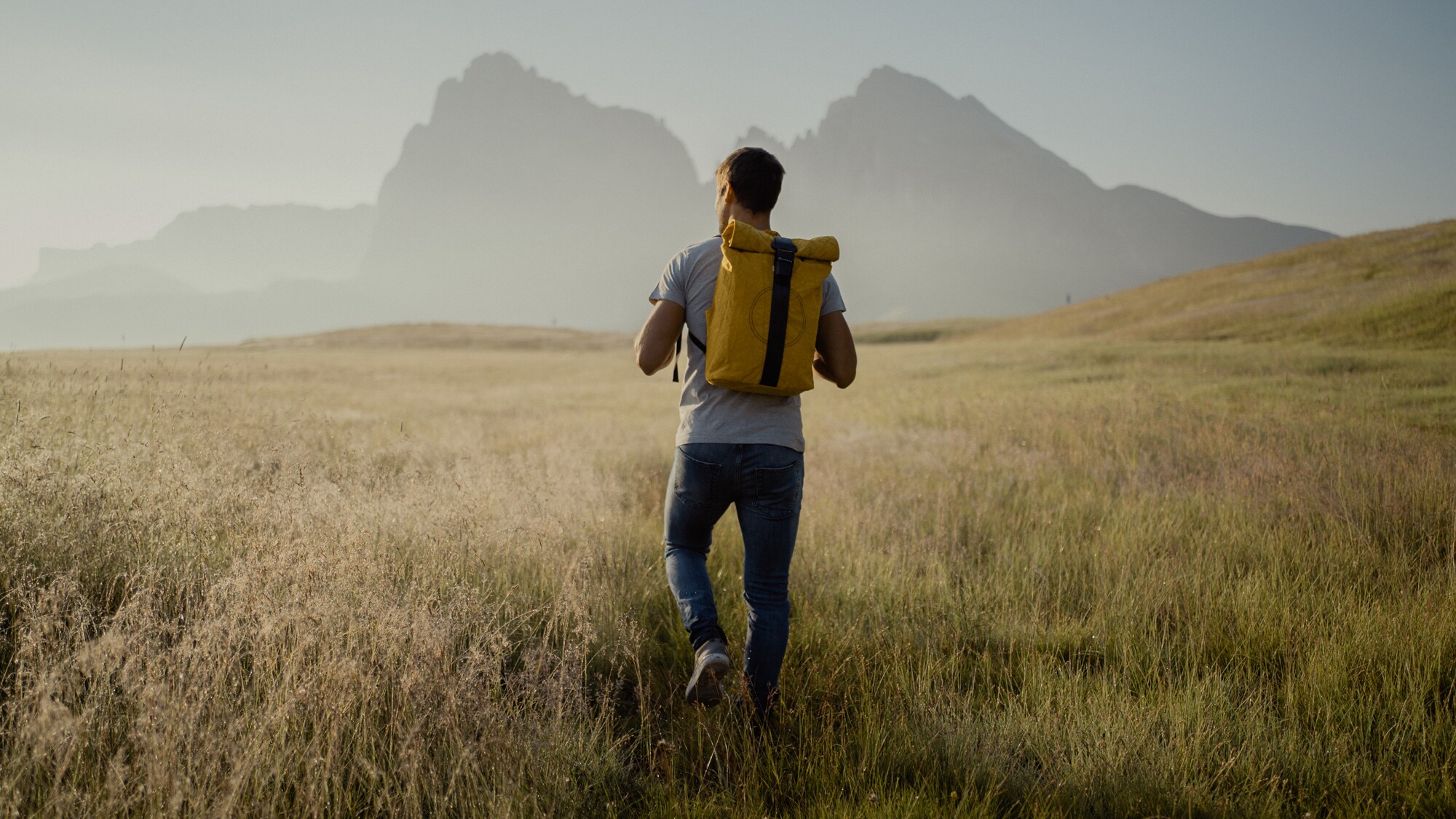 Ein Mann trägt einen Rucksack von Airpaq auf dem Rücken und geht durch die Natur.