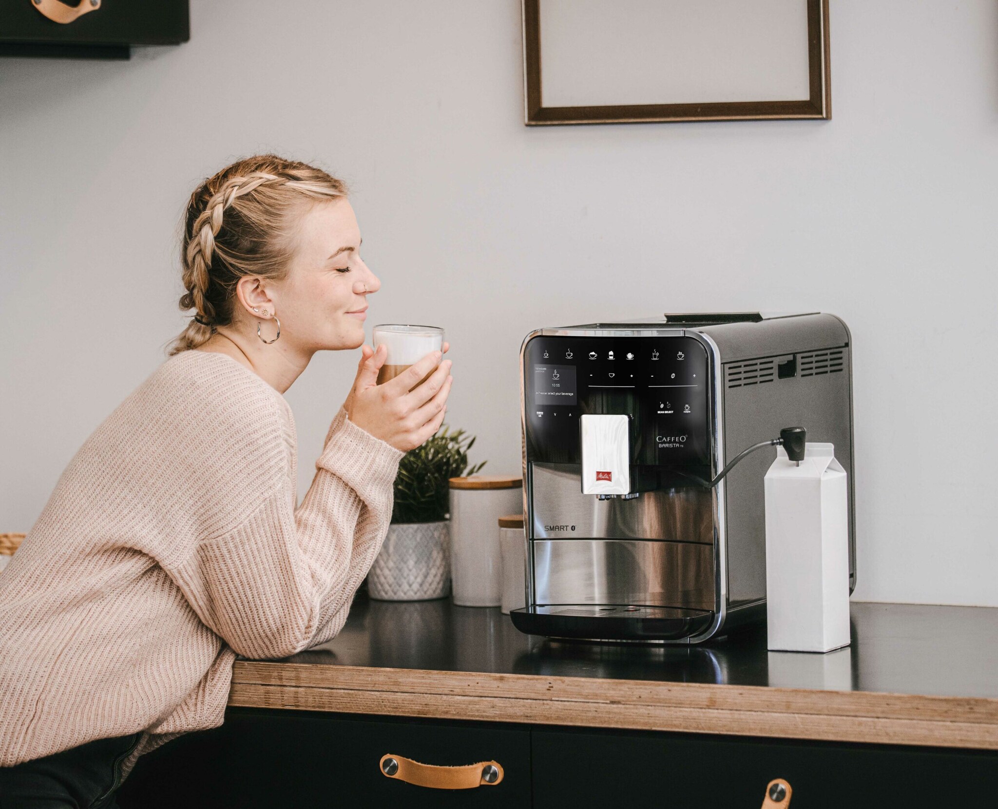 Eine Frau sitzt vor einer Kaffeemaschine und genießt ihren Kaffee