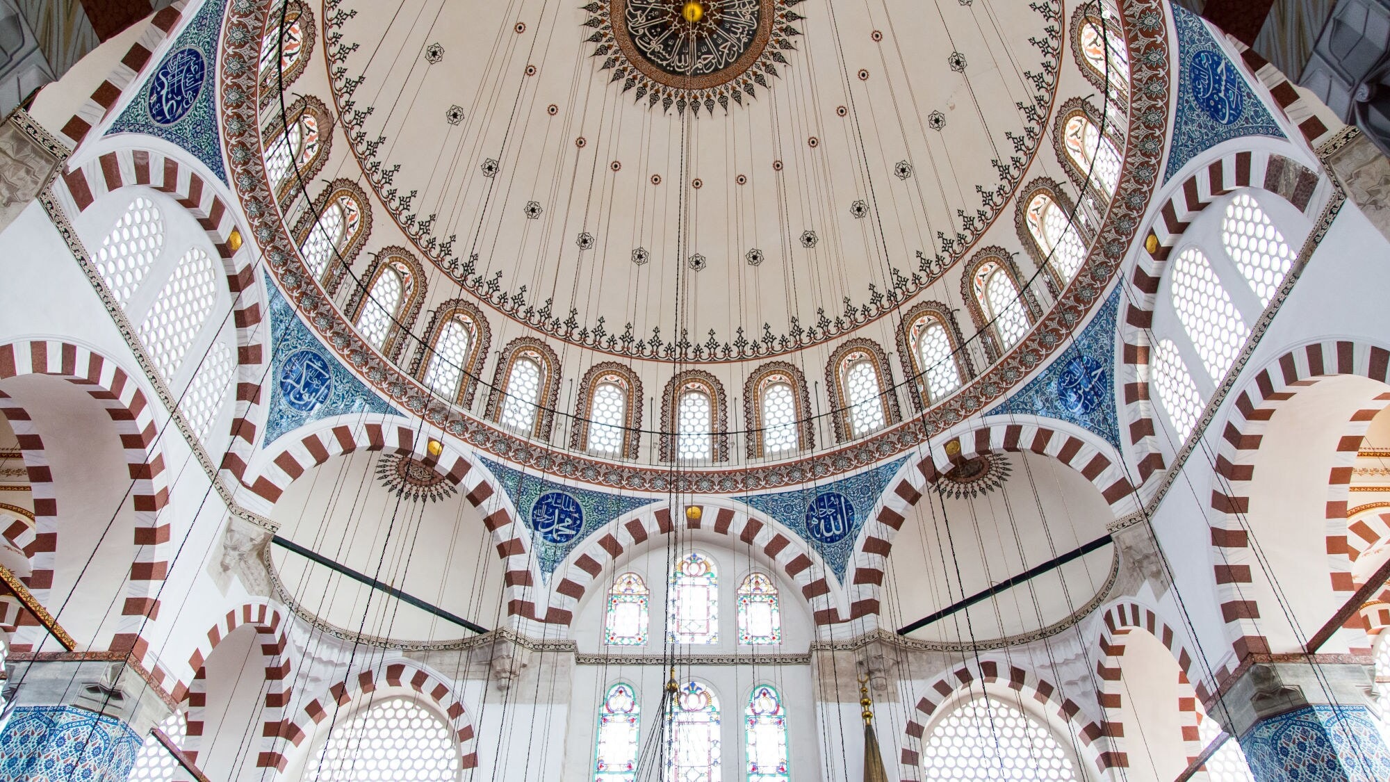 Innenansicht eines hellen Kuppeldachs einer Moschee mit blauen Kachelverzierungen. Innenansicht eines hellen Kuppeldachs einer Moschee mit blauen Kachelverzierungen.