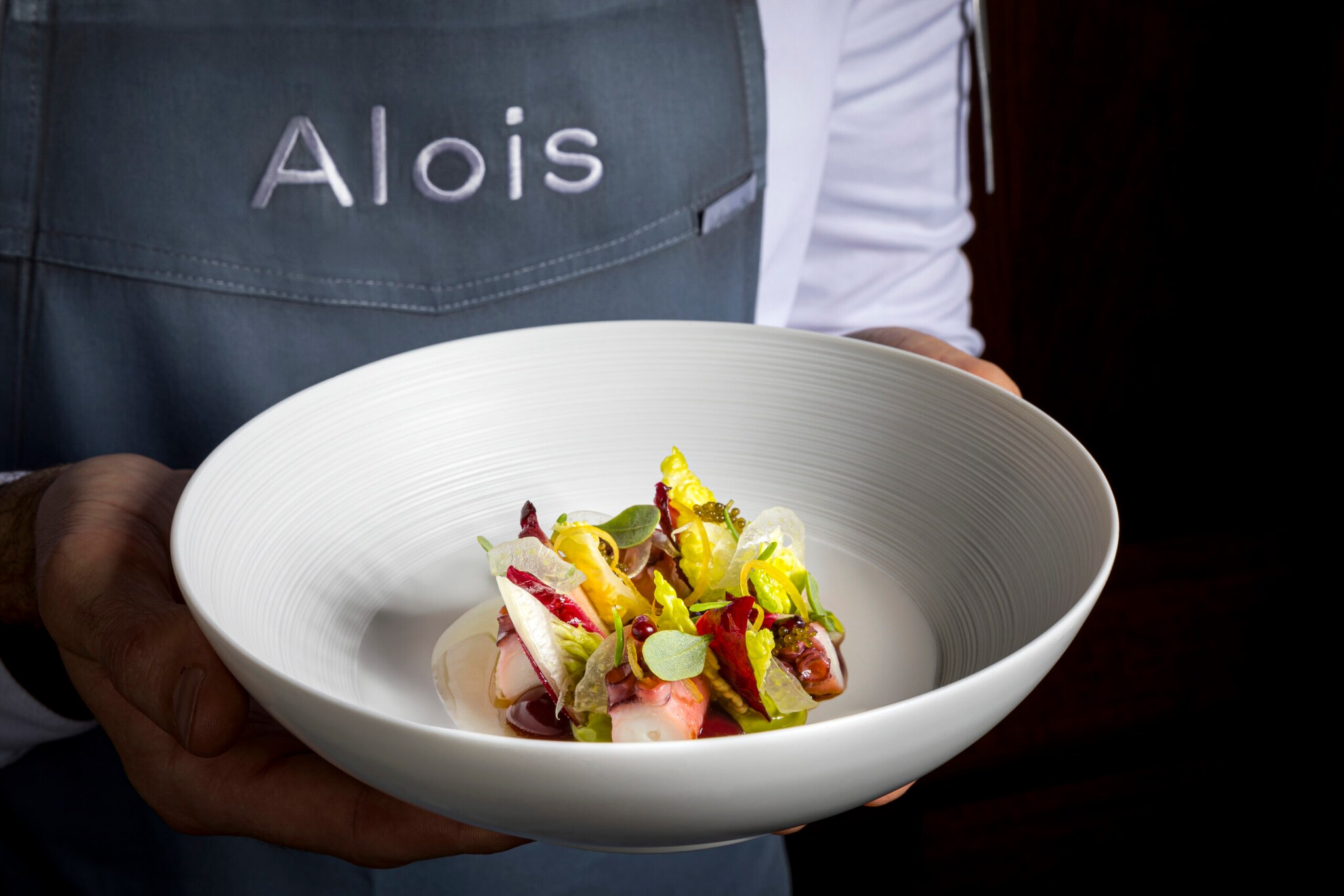 Eine Person hält einen weißen Teller mit buntem Gericht darauf