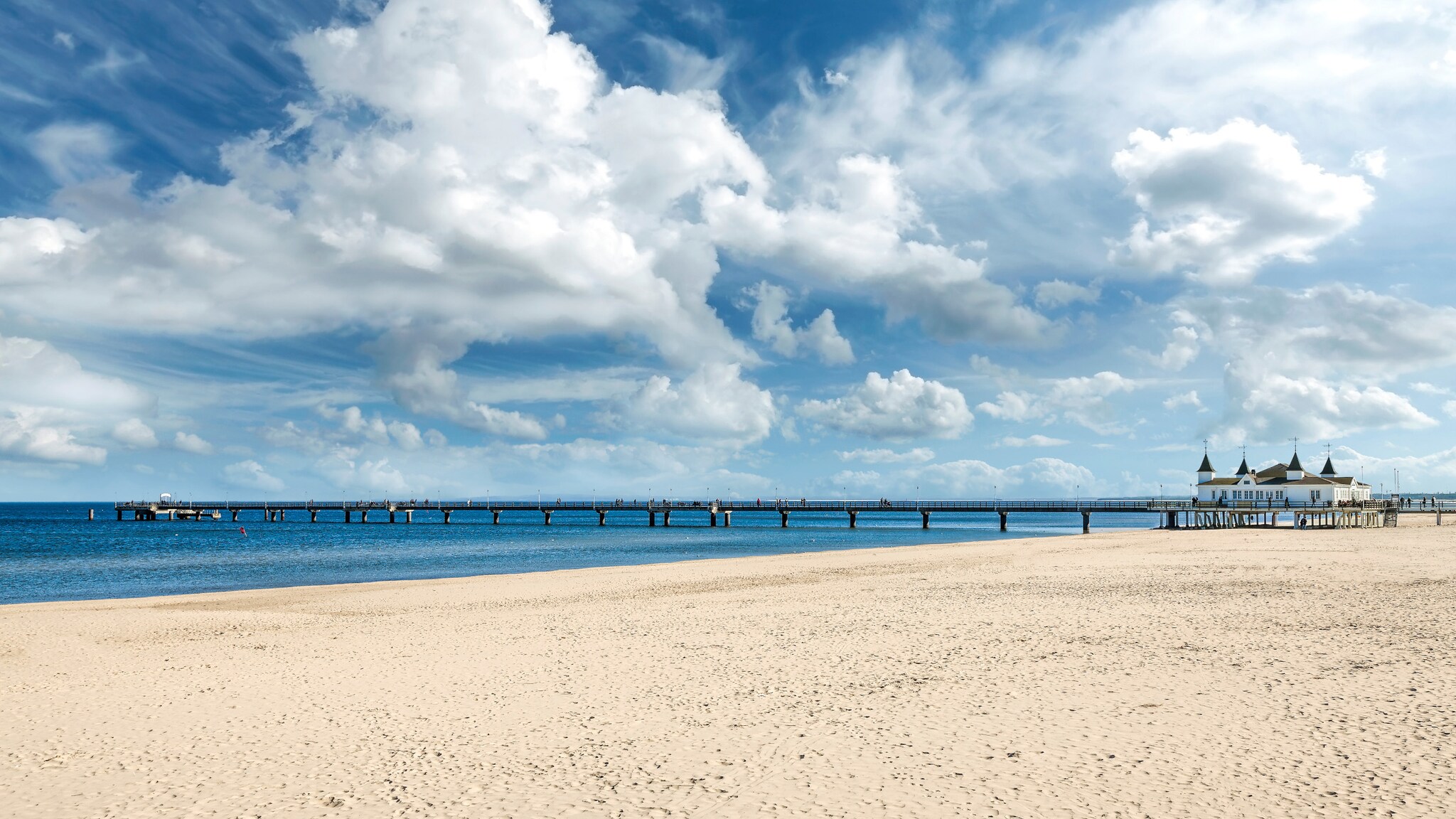 Menschenleerer, breiter Sandstrand mit Pier