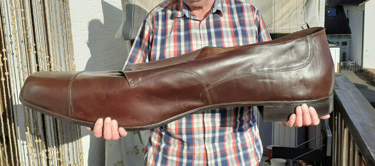Ein Mann hält einen braunen Lederschuh in Schuhgröße 150 Ein Mann hält einen braunen Lederschuh in Schuhgröße 150
