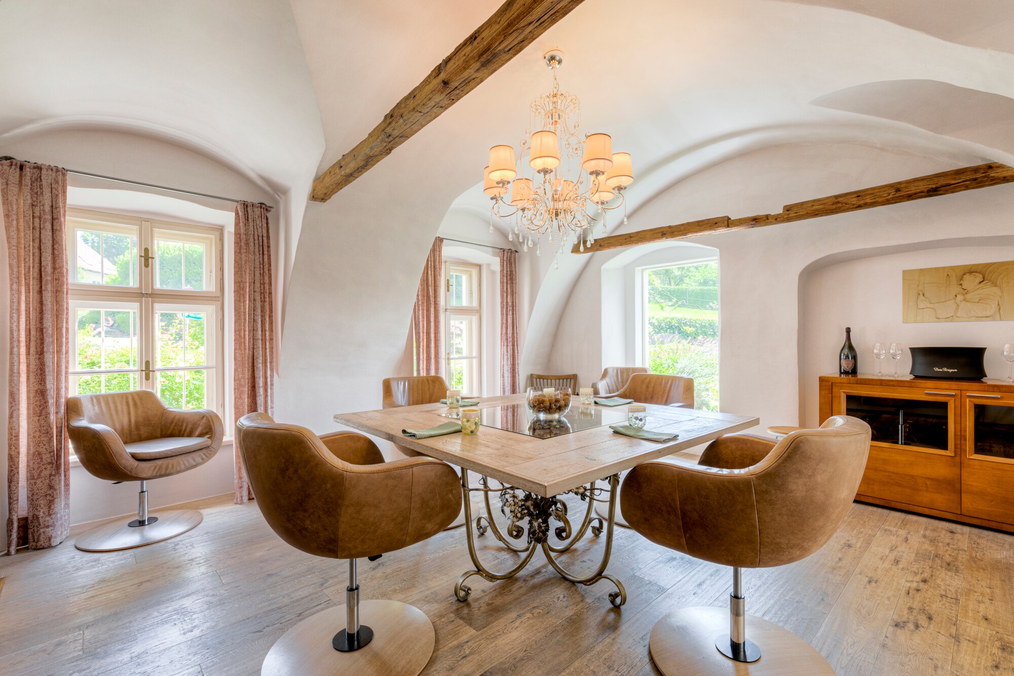 Ein heller Raum mit Fenstern, in dessen Mitte ein viereckiger, eingedeckter Tisch mit braunen Ledersesseln steht Ein heller Raum mit Fenstern, in dessen Mitte ein viereckiger, eingedeckter Tisch mit braunen Ledersesseln steht